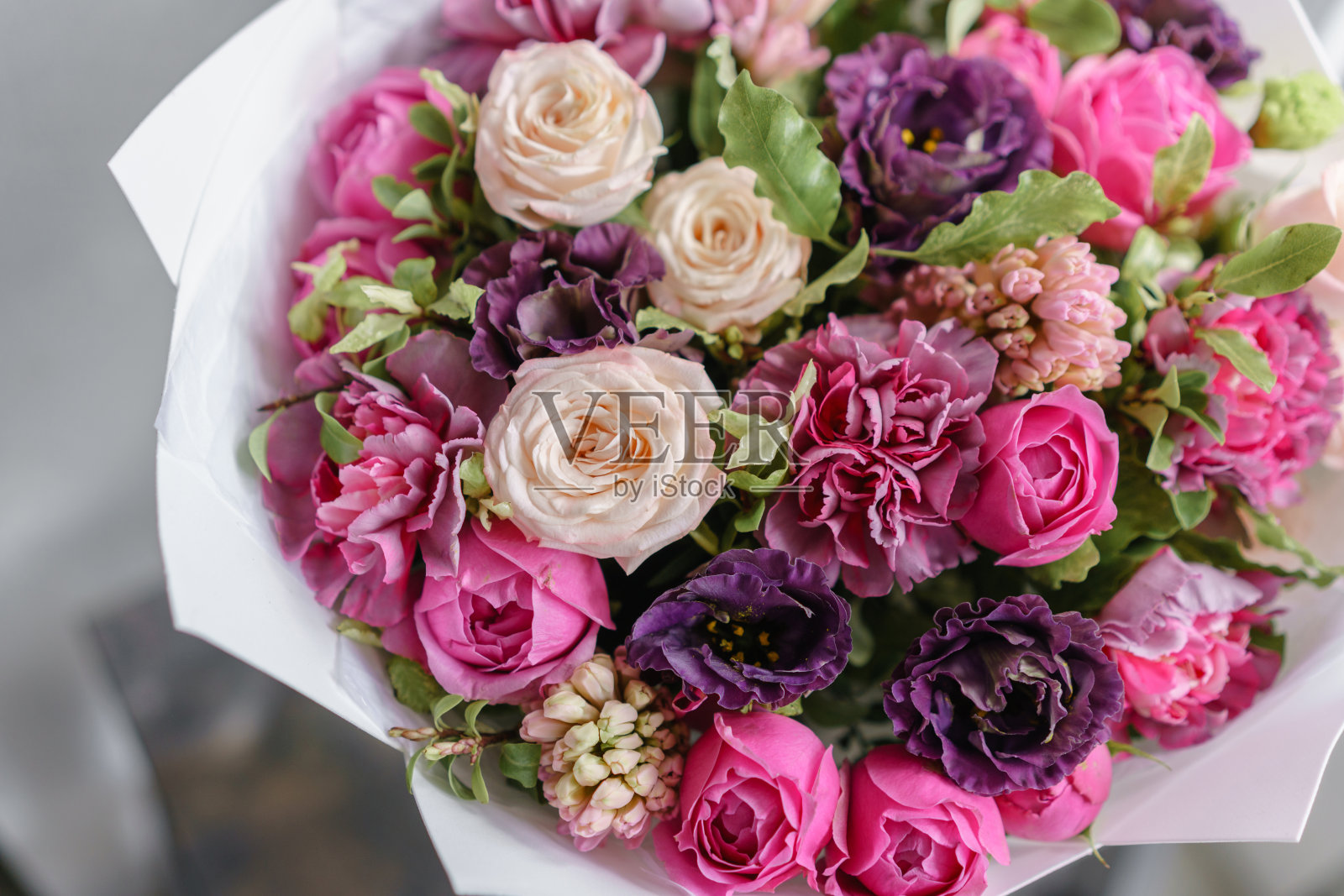 木桌上摆着一束紫色和粉红色的美丽鲜花。花卉栽培技术的概念。春天的颜色。花店花匠的工作。垂直图照片摄影图片
