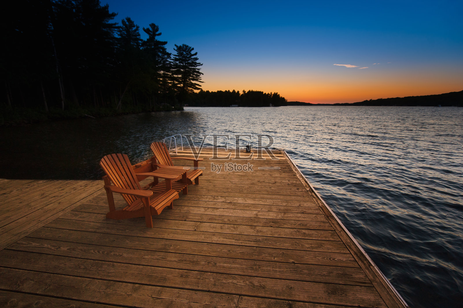 日落时分，木制码头上放着两把阿迪朗达克式的椅子照片摄影图片