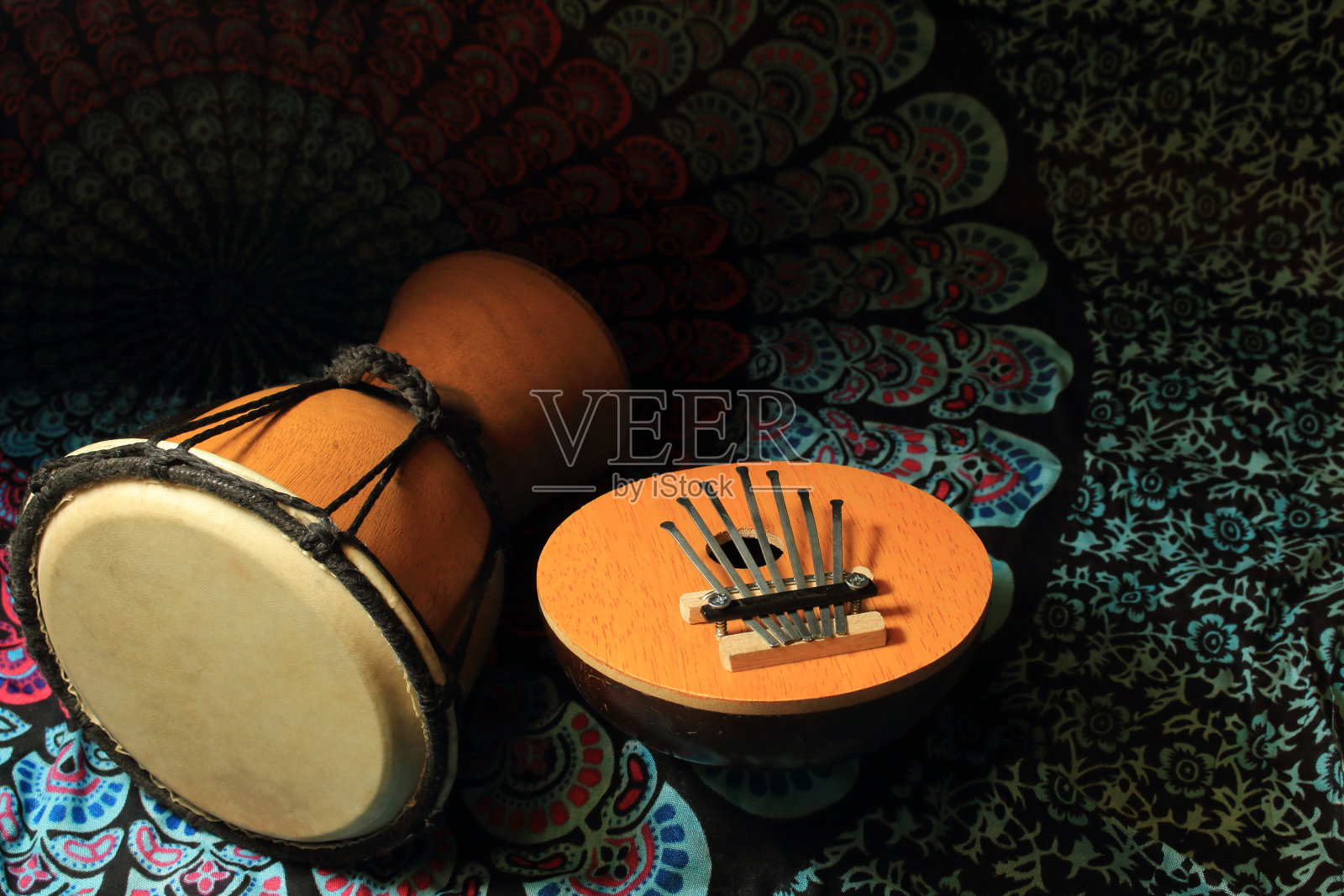两种非洲乐器(卡林巴，鼓)躺在一条彩色的围巾上。照片摄影图片