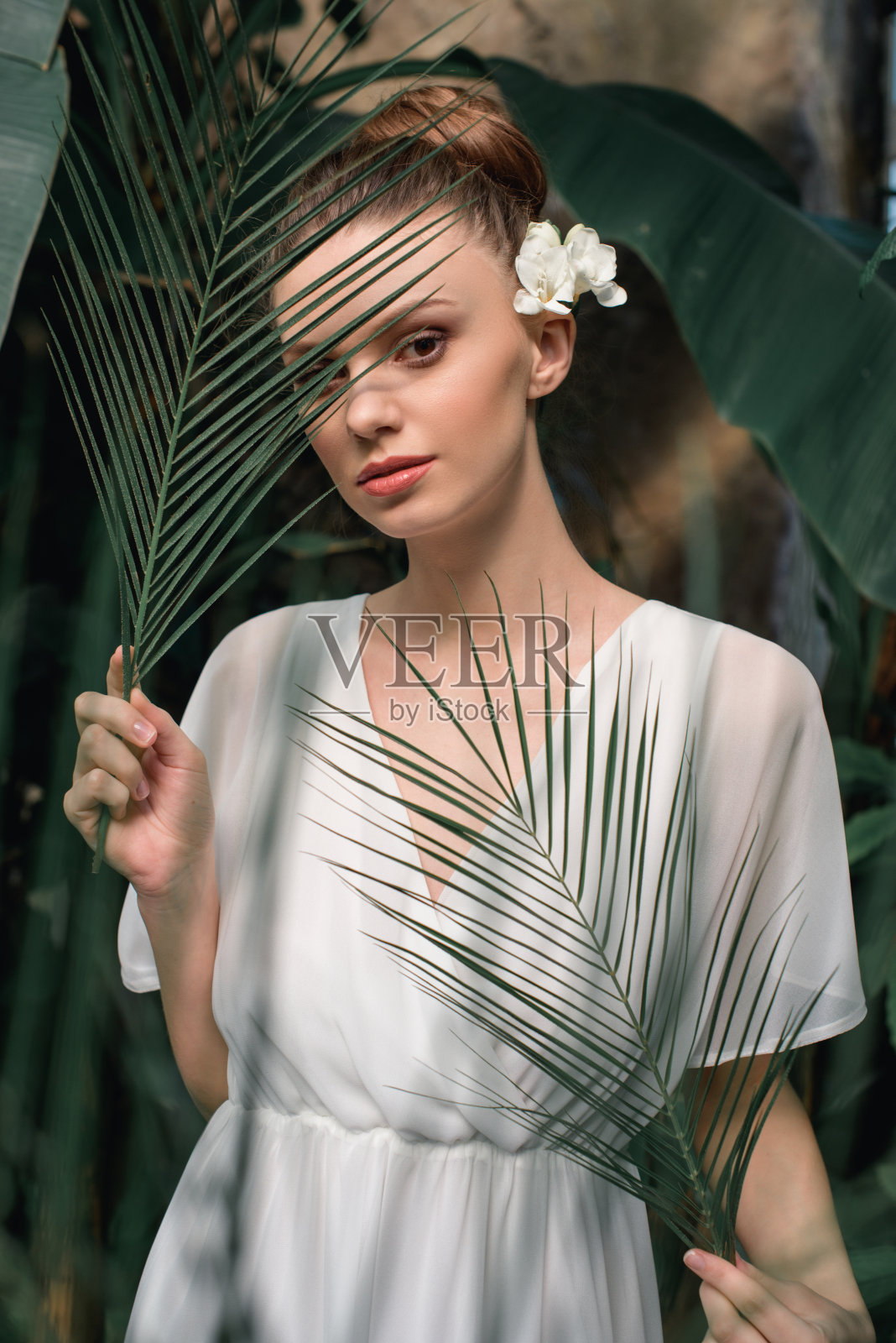 美丽的女孩在白色的夏装与热带棕榈叶摆姿势照片摄影图片