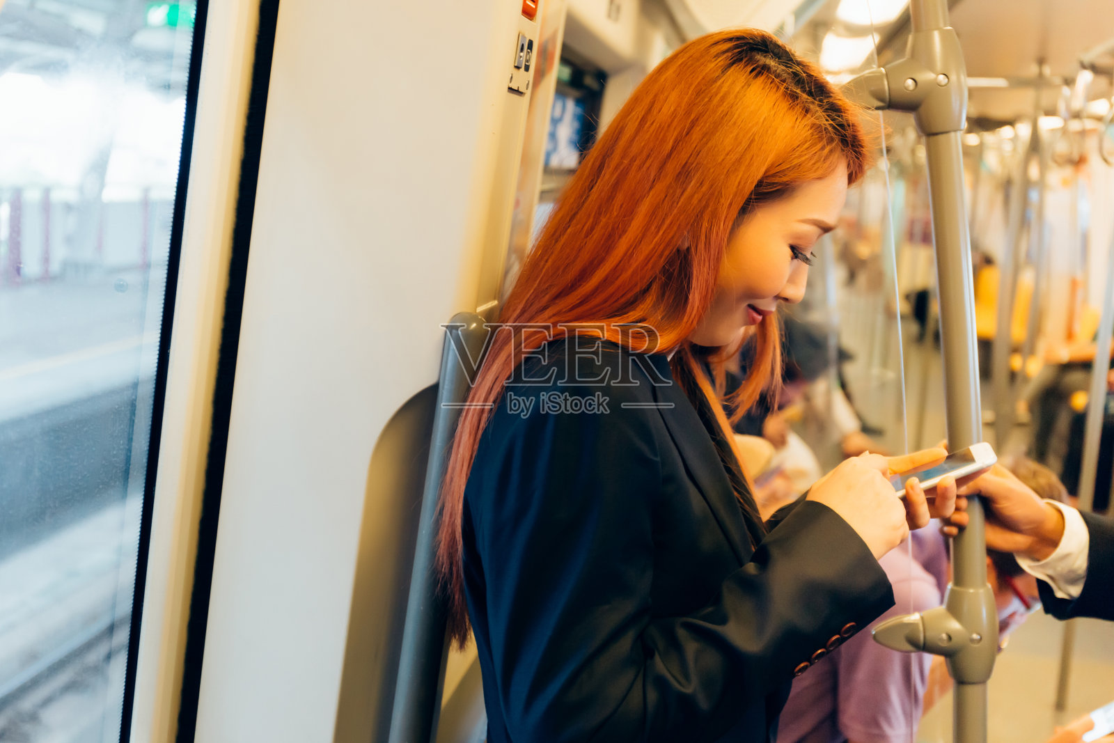 快乐漂亮的亚洲商务女性在公共交通工具上玩手机，照片摄影图片