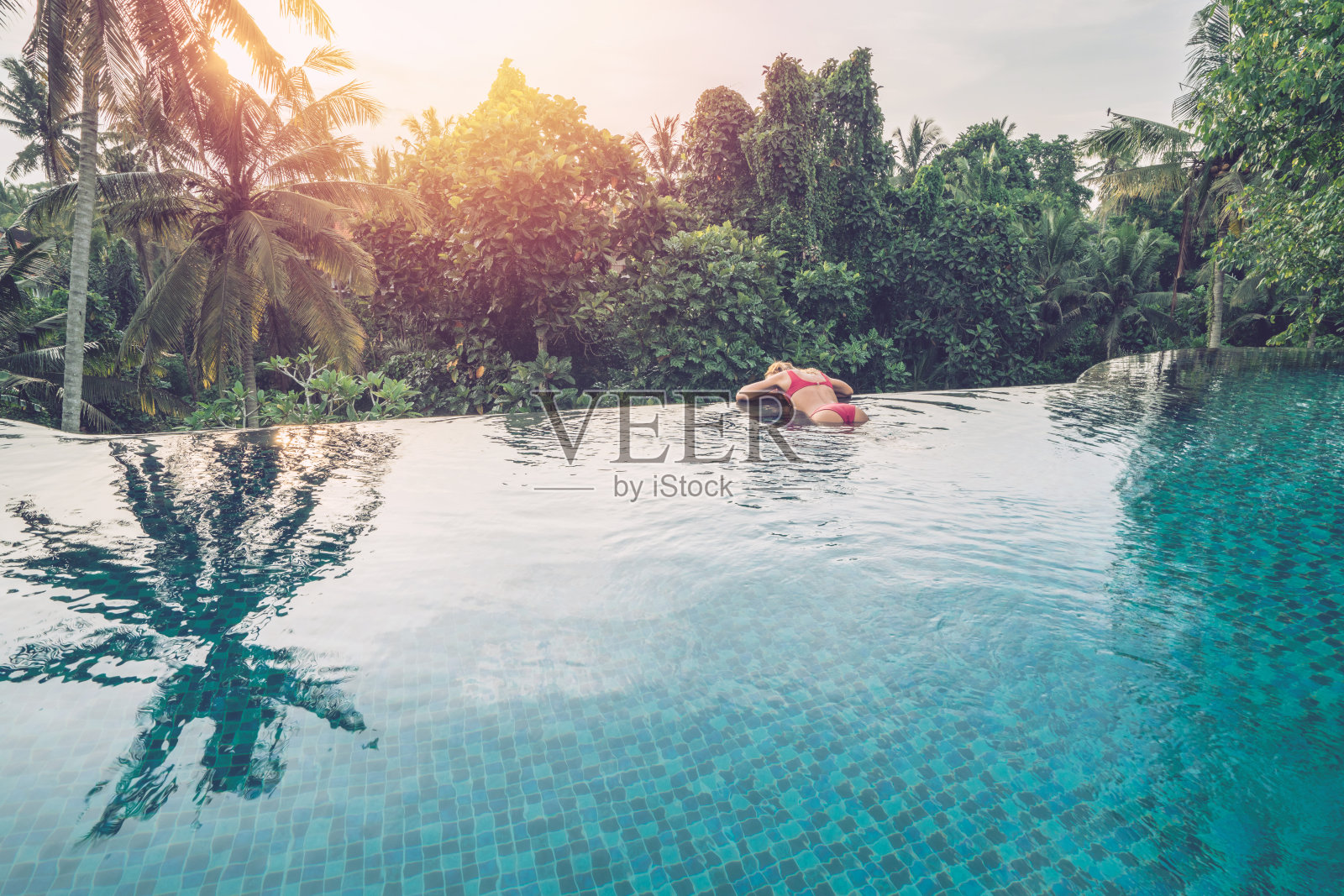 年轻女子在一个无边泳池边，乌布，巴厘岛享受热带气候假期的亚洲照片摄影图片