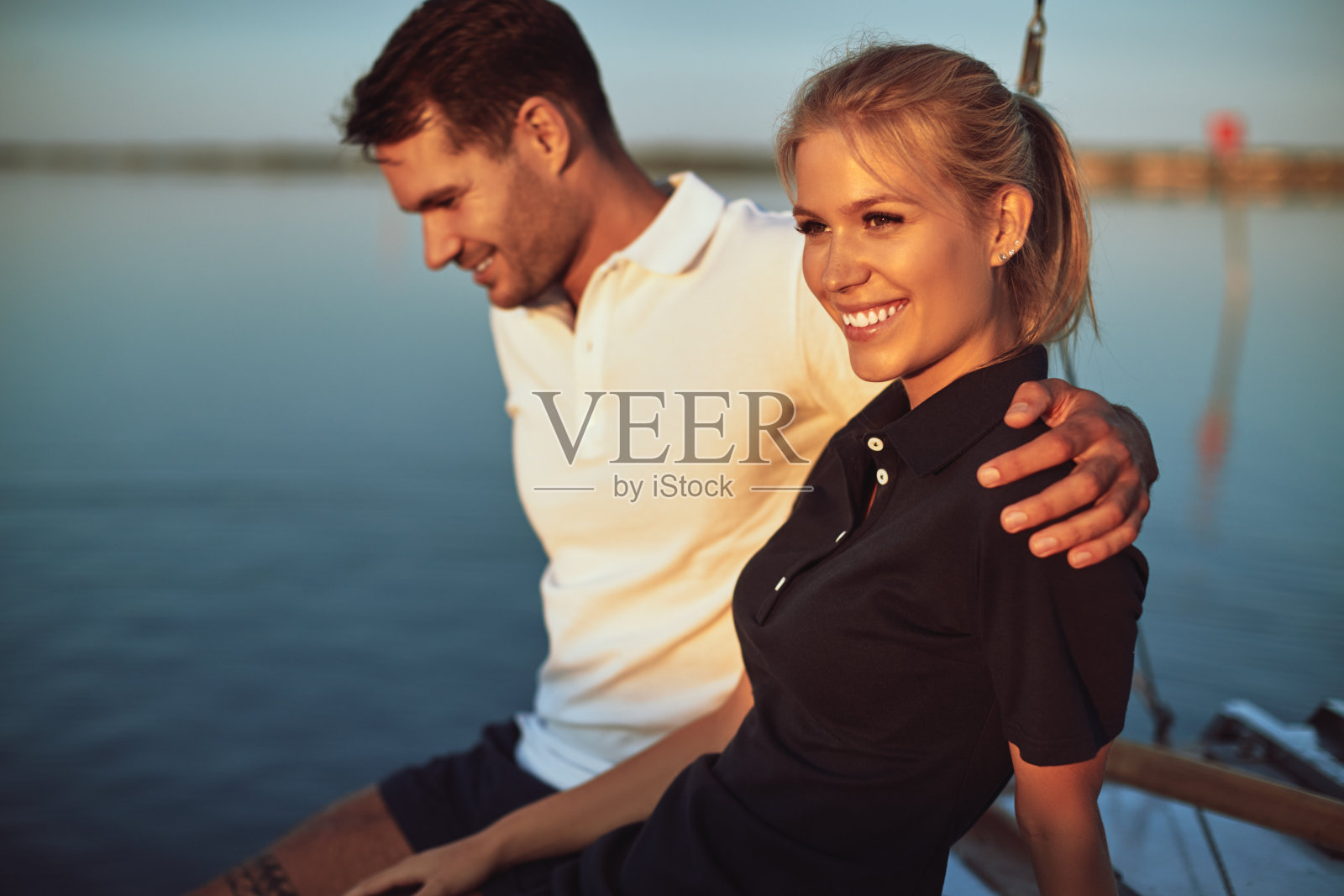 微笑的年轻女人和她的丈夫坐在游艇上照片摄影图片
