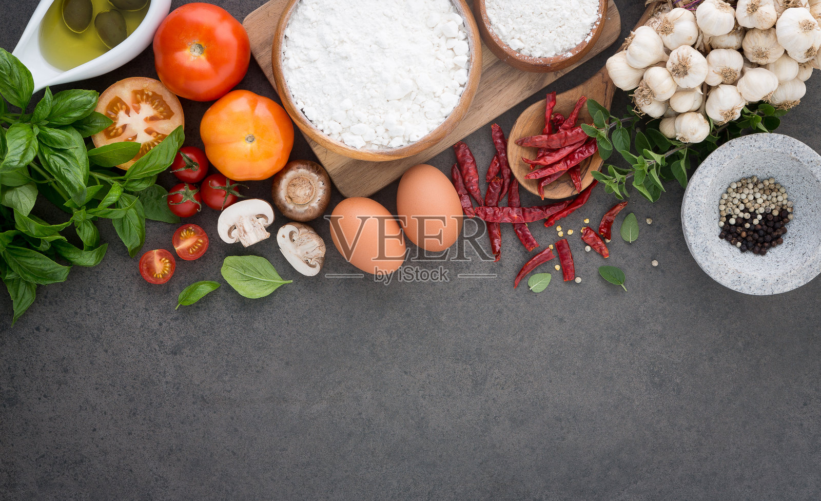 意大利菜背景，有西红柿，罗勒，蘑菇，橄榄，橄榄油，大蒜，胡椒，辣椒，鸡蛋，面粉和牛至。板岩的背景。照片摄影图片