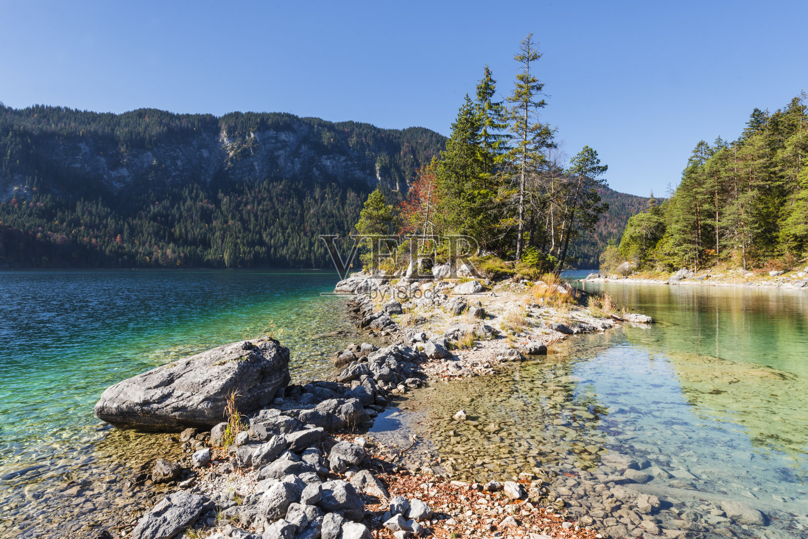 德国巴伐利亚州，在Eibsee湖，被秋季森林包围的Braxeninsel岛的海角岸边的石头照片摄影图片