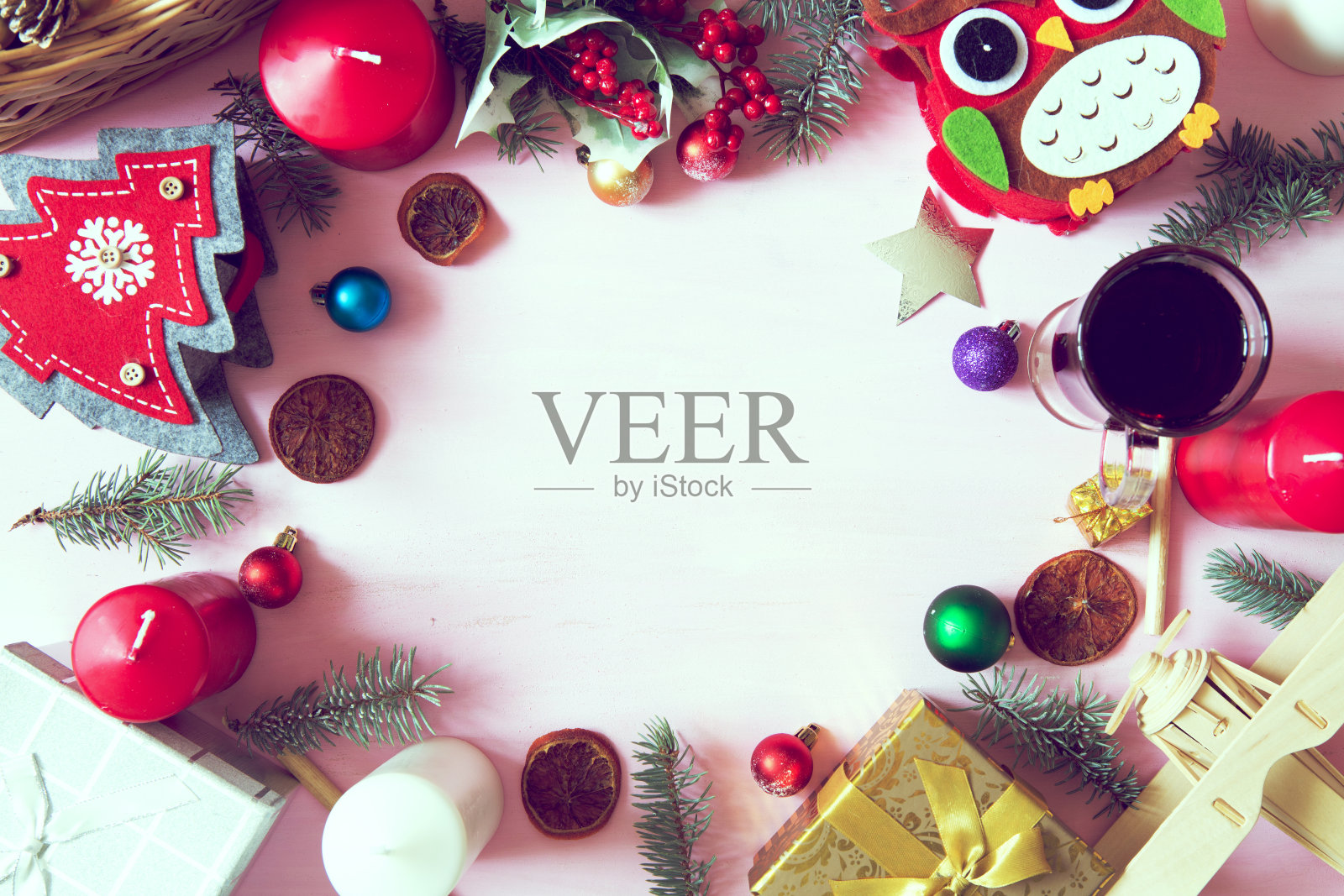 圣诞框架或边框上有大量的圣诞道具，装饰品，球，礼物和蜡烛在一个粉红色的木制背景松树枝和copyspace，俯瞰照片摄影图片