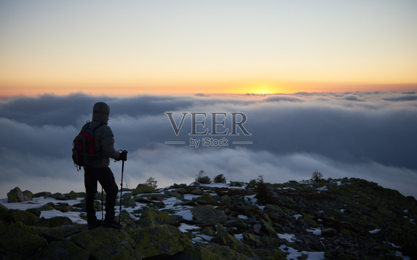 游客背包徒步在岩石山顶，背景是雾谷和日出时的蓝天。照片摄影图片
