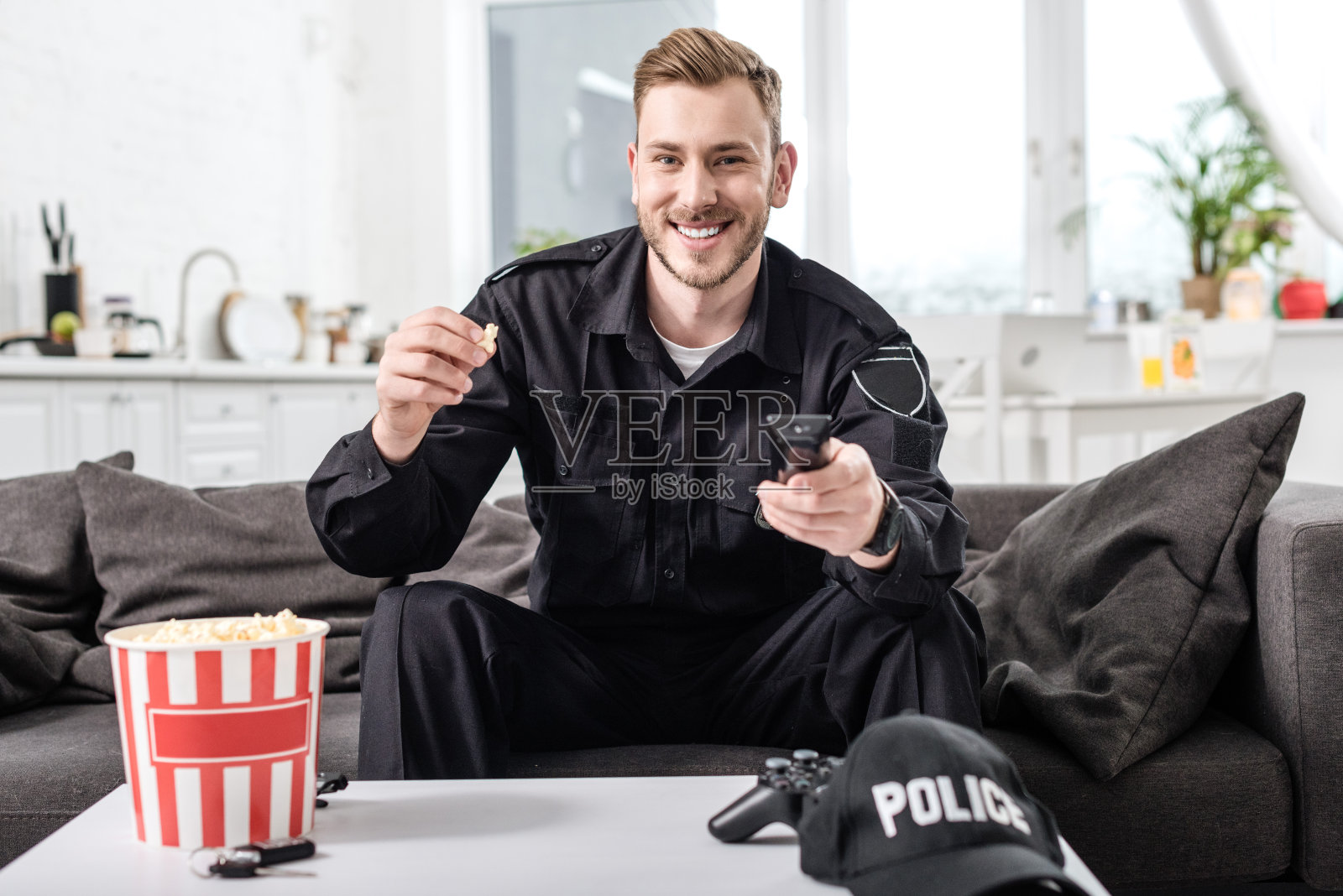 一名警察坐在沙发上，手里拿着遥控器，吃着爆米花照片摄影图片