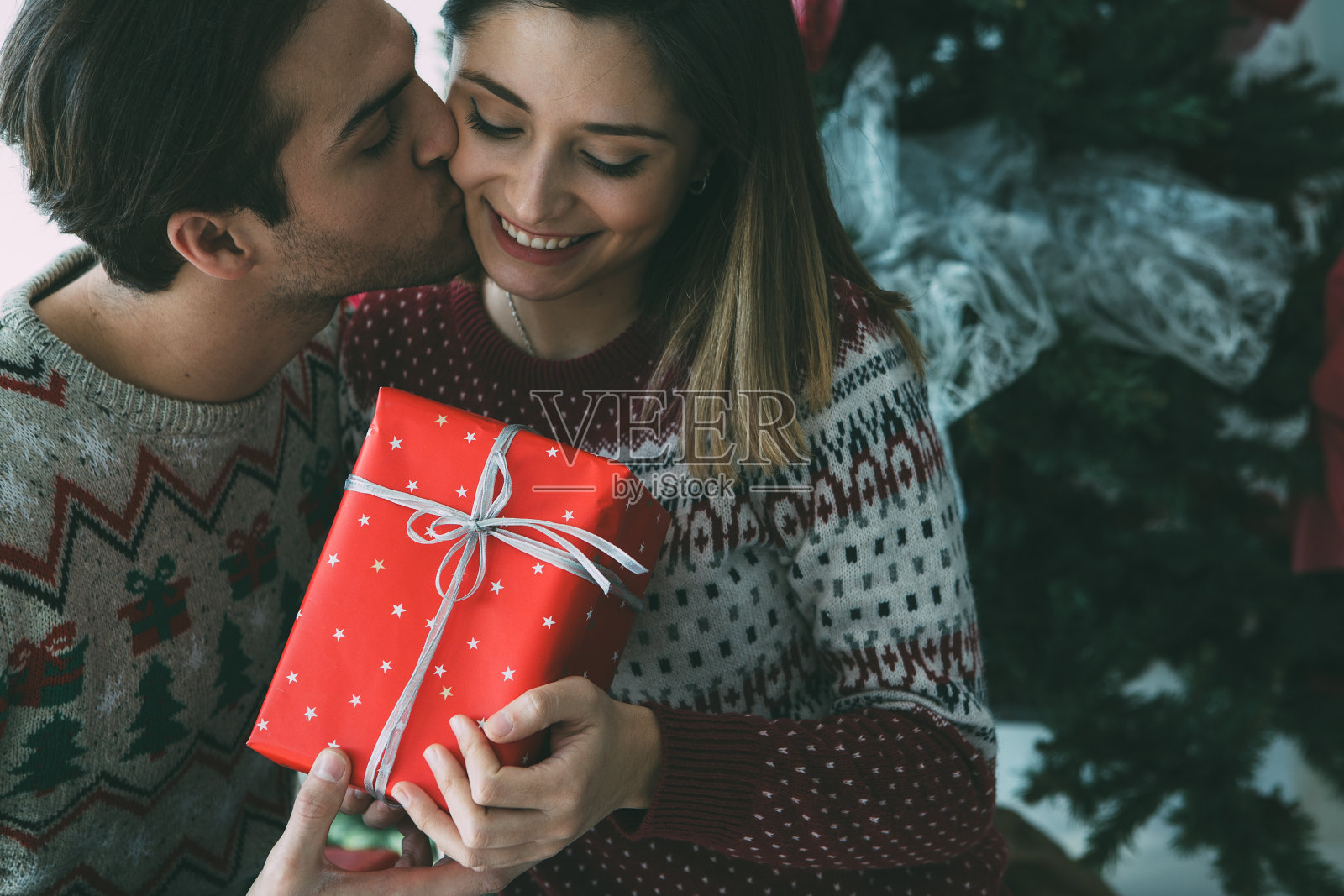 年轻男子在圣诞节亲吻心爱的女子照片摄影图片