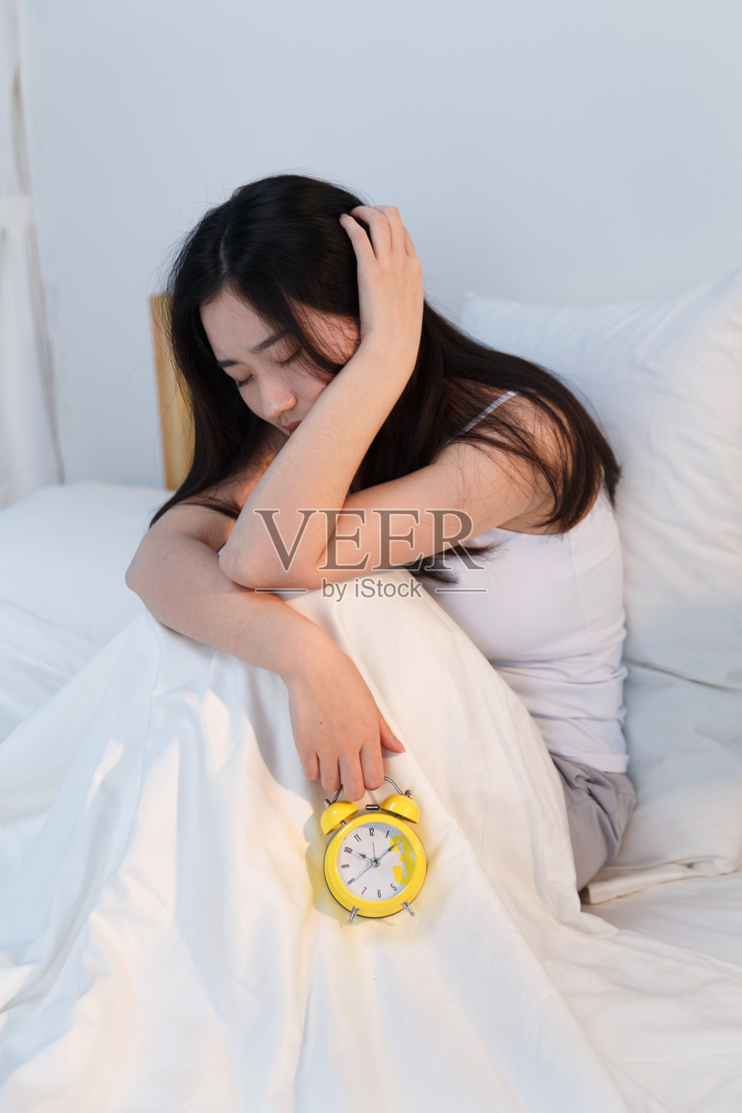 情绪低落的青年女人坐在卧室的床上照片摄影图片
