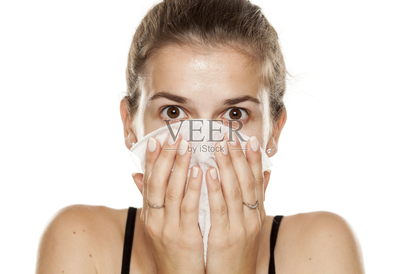年轻女子清洁她的脸与湿擦在白色的背景照片摄影图片