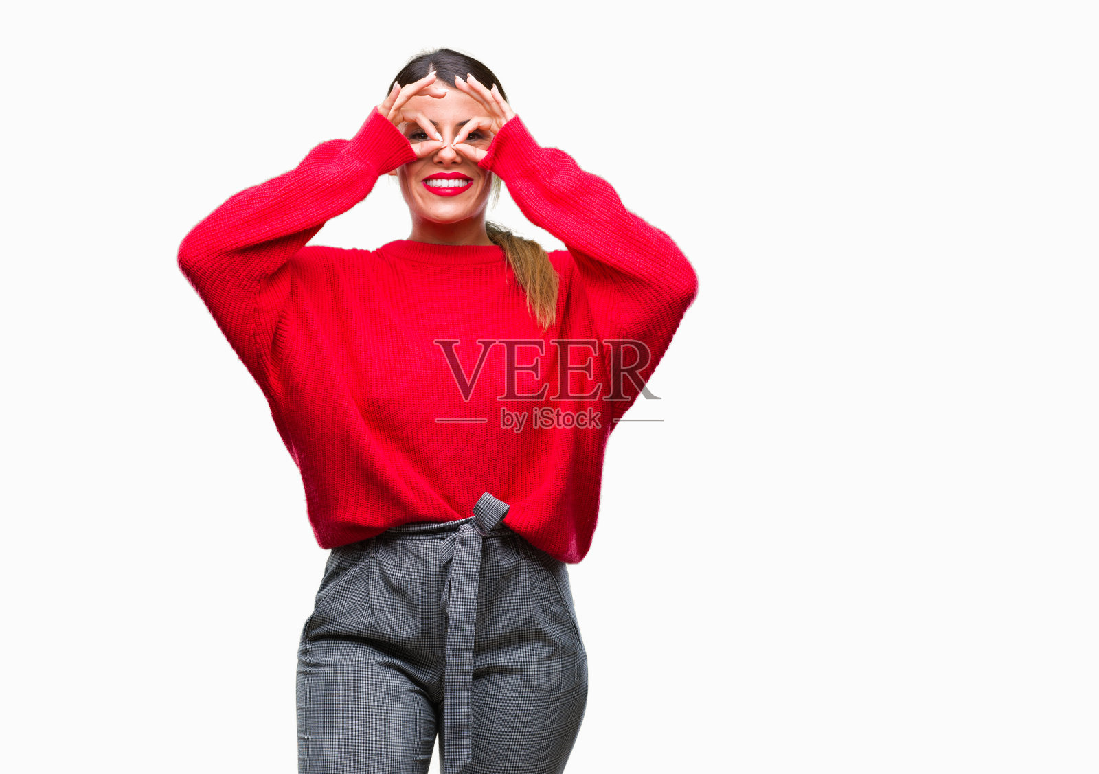 年轻美丽的商业女人穿着冬季毛衣在孤立的背景做着不错的手势，像望远镜伸出舌头，眼睛透过手指看。疯狂的表情。照片摄影图片