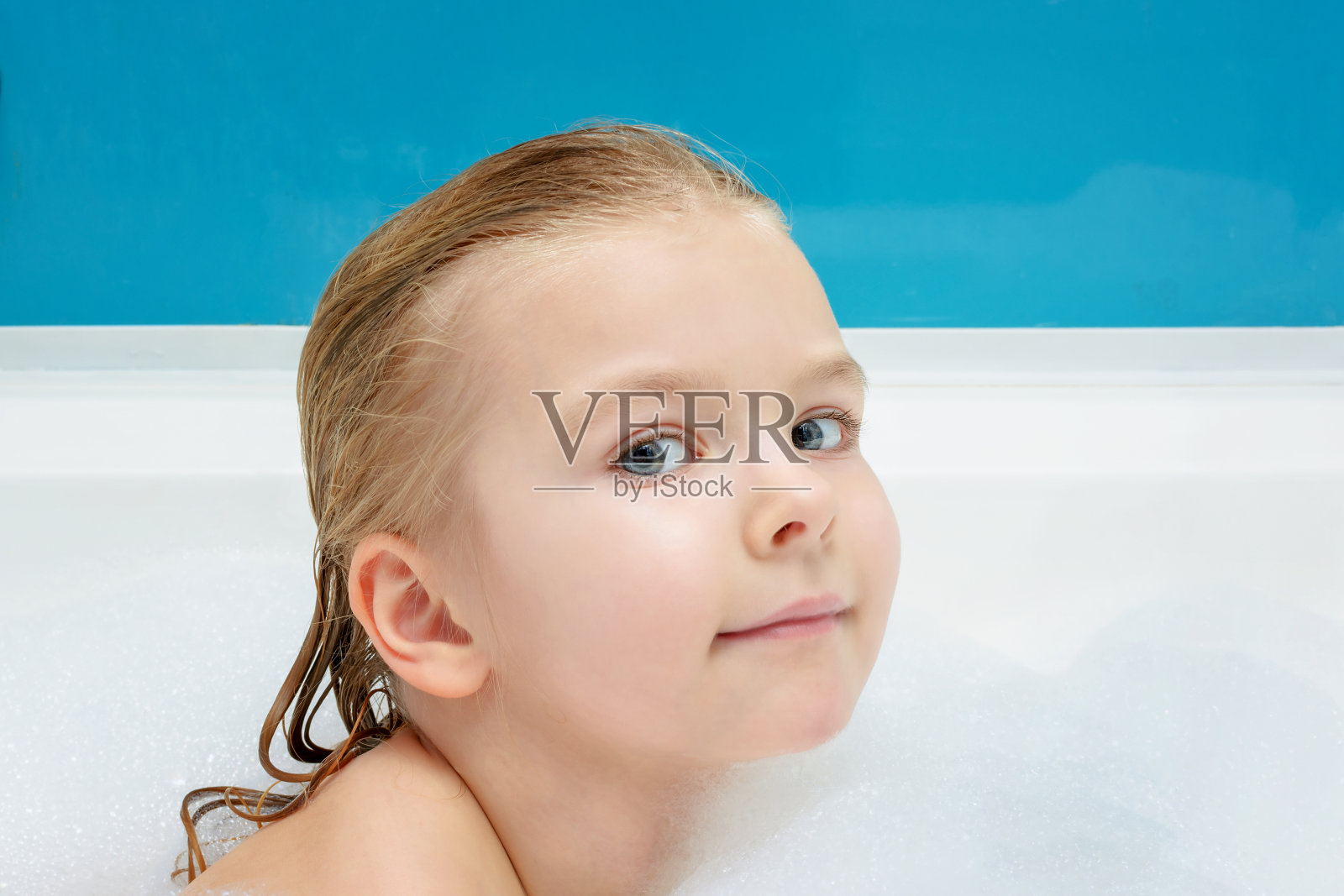 一个美丽的小女孩在泡沫中游泳。可爱的孩子微笑。光照片。照片摄影图片