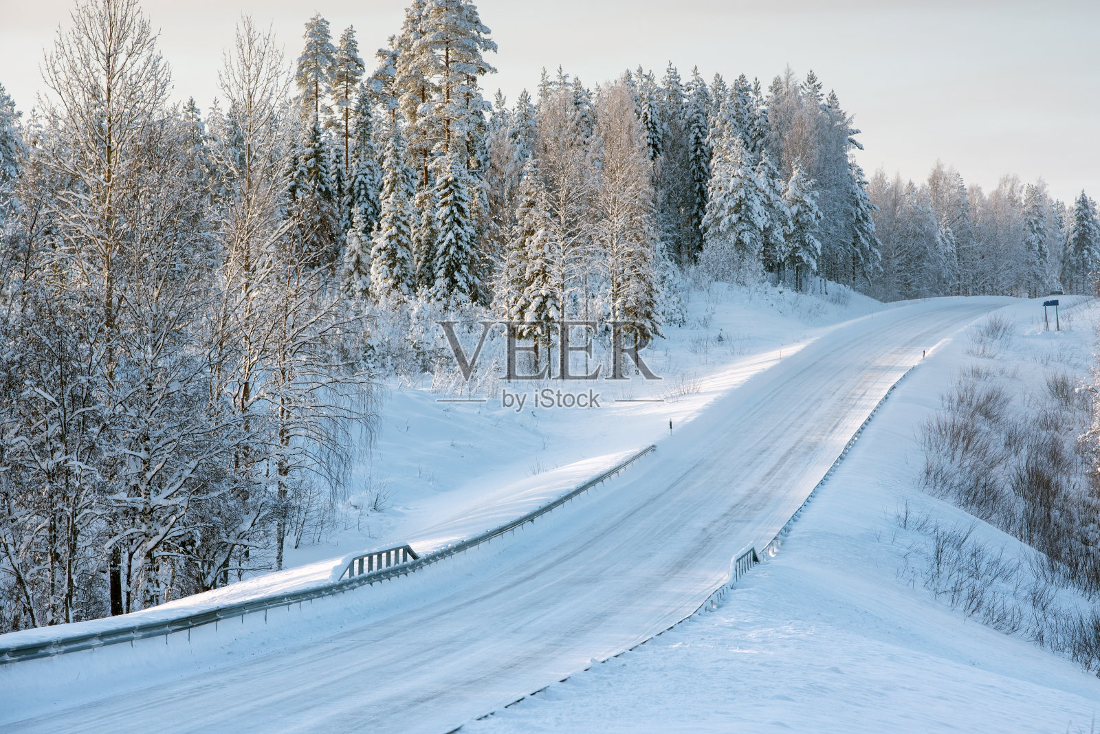 芬兰东部冰雪覆盖的道路蜿蜒穿过冬季的森林景观照片摄影图片