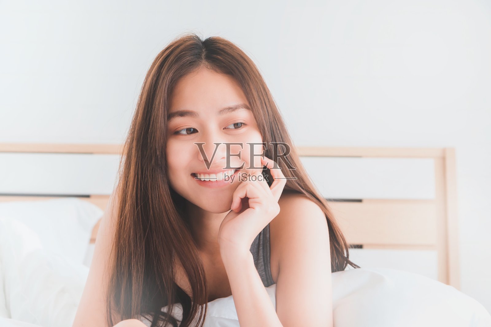 年轻的亚洲美丽的女人微笑和放松在床上的卧室。健康美丽的女性理念。照片摄影图片