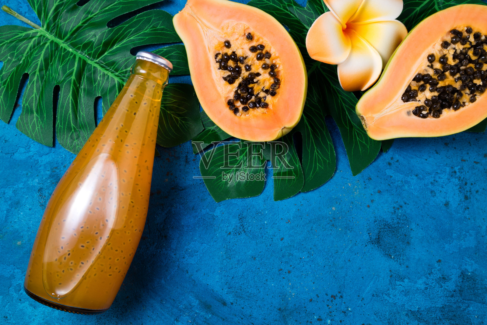 夏季的热带背景与异国情调的果汁木瓜奇亚籽，绿色的棕榈叶上的蓝色。水果背景和夏季饮料。俯视图照片摄影图片