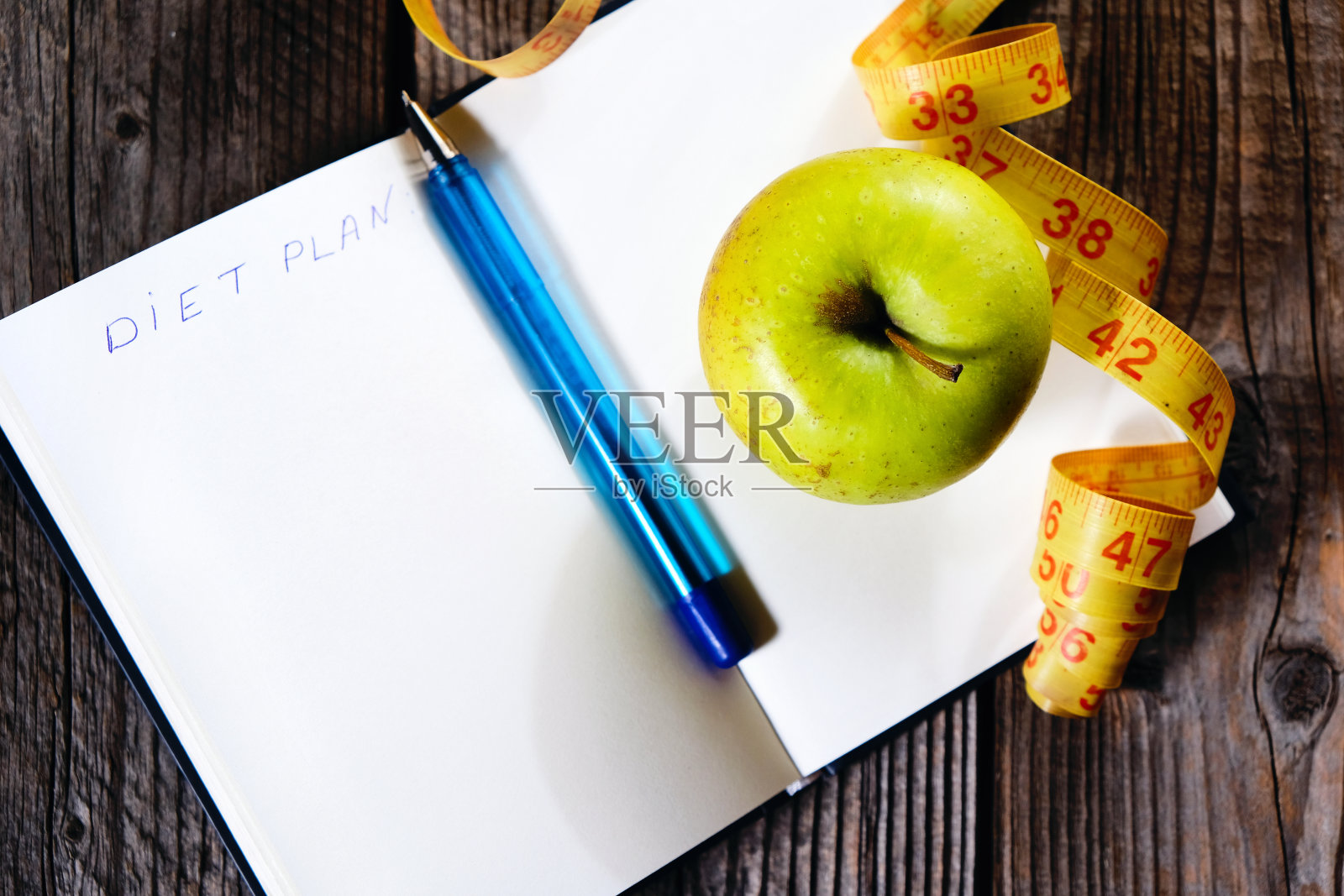 空白打开笔记本，绿色苹果和黄色厘米胶带。概念运动、饮食、健身、健康饮食。照片摄影图片