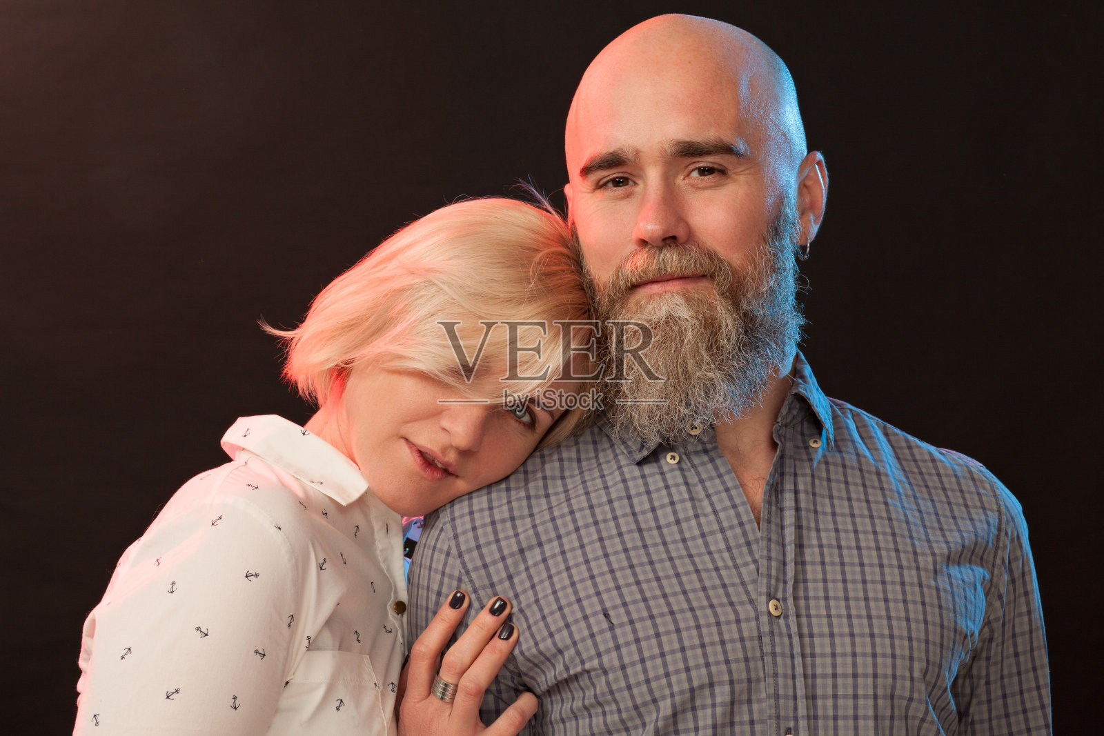 一个迷人的中年异性恋夫妇的工作室肖像在一个黑色的背景照片摄影图片