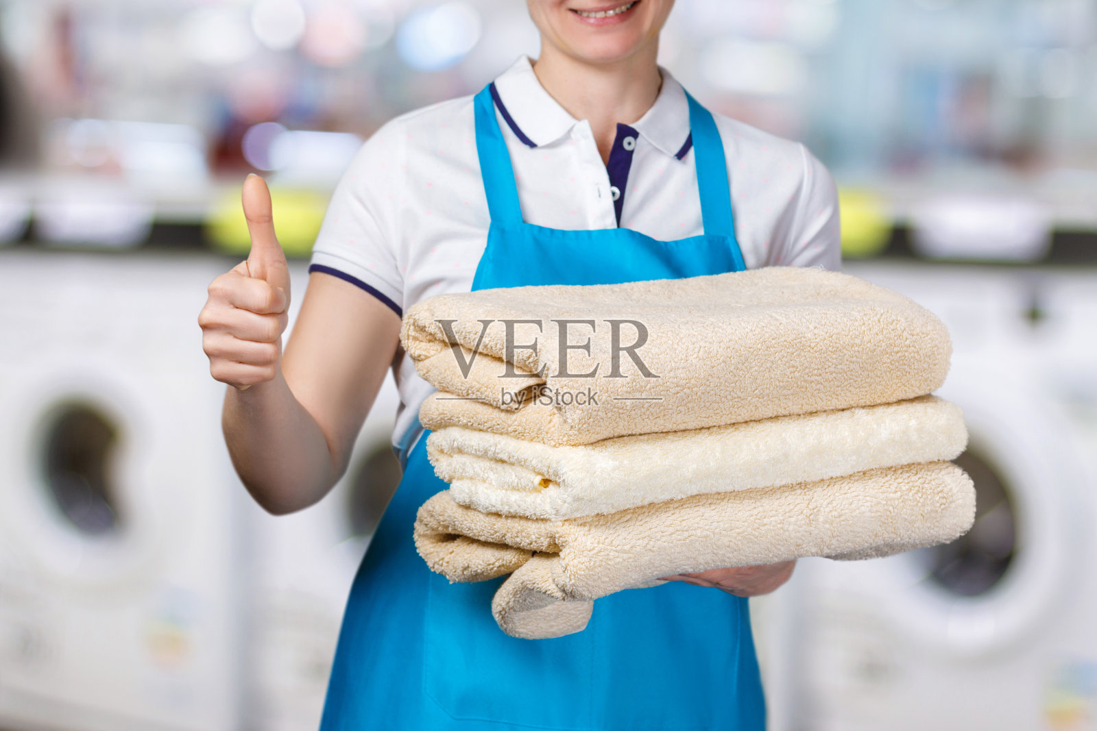 一个洗衣工人拿着干净的毛巾。照片摄影图片