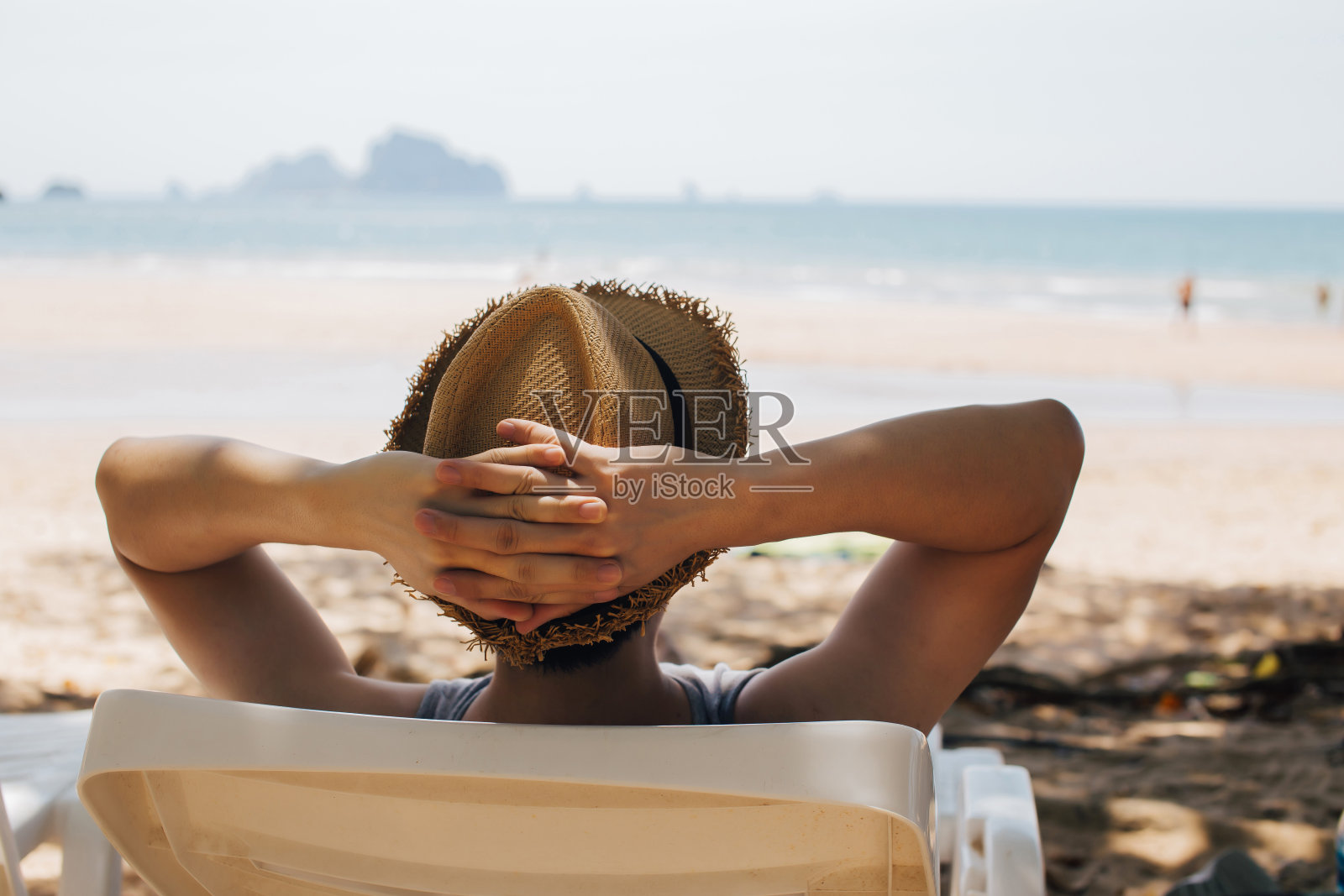 年轻男性旅行者放松和坐在沙滩椅上的特写-暑假的概念照片摄影图片