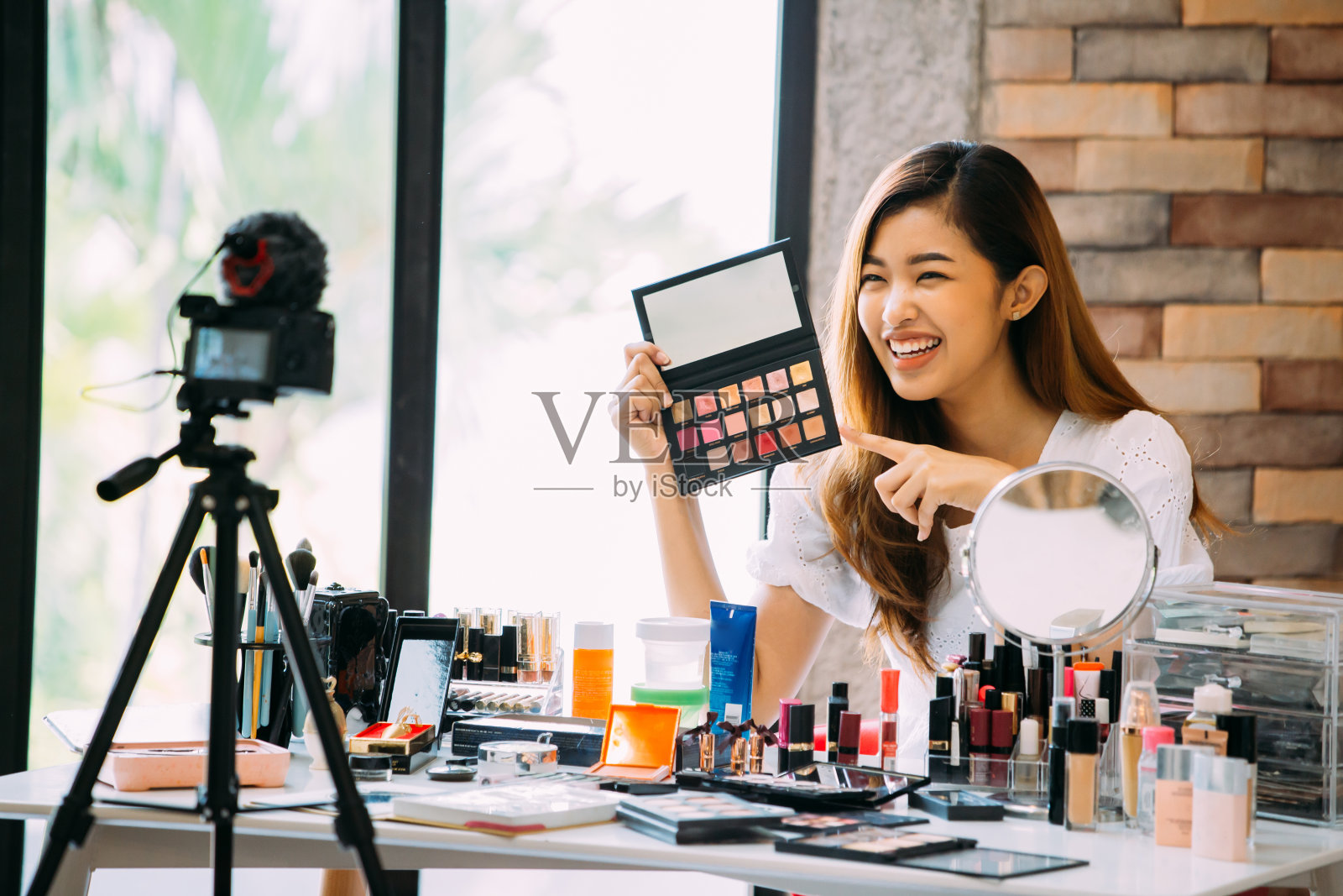 迷人的亚洲女孩录制视频博客。在镜头前展示化妆品的美容博主照片摄影图片