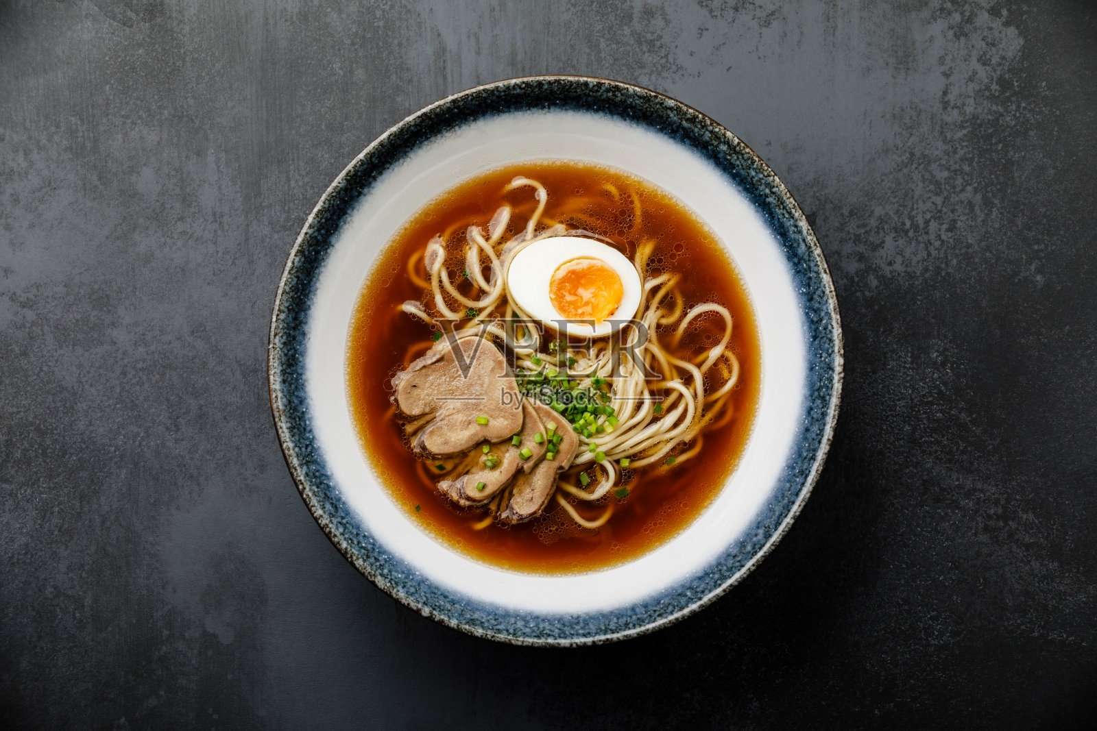 亚洲拉面肉汤牛肉舌肉和Ajitama腌制鸡蛋在碗中，深色背景照片摄影图片