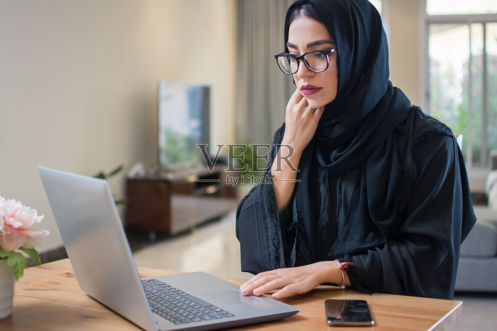 沉思或担忧的阿拉伯妇女在家里使用笔记本电脑照片摄影图片