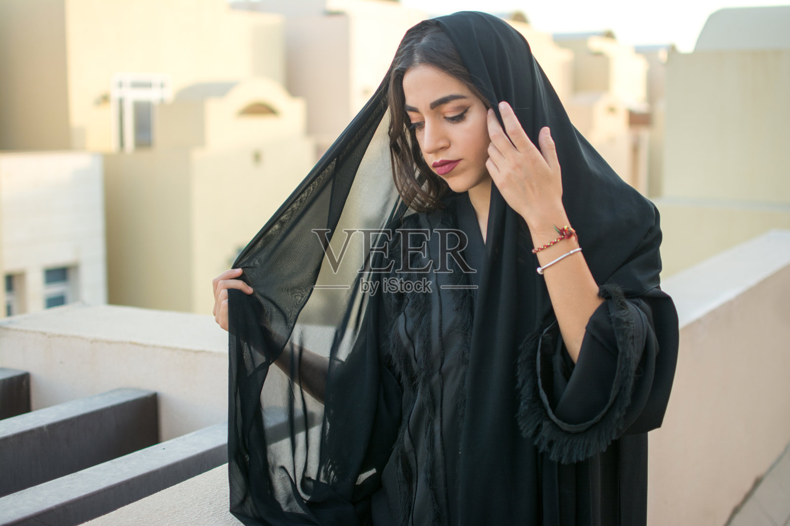 美丽的中东年轻女子的肖像，穿着传统的阿拉伯服装站在外面看阳台照片摄影图片