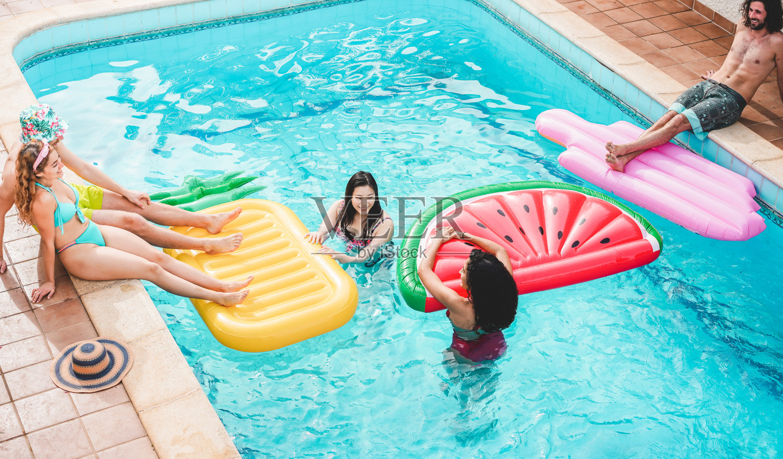 快乐的朋友漂浮与气垫球在游泳池派对-年轻人有乐趣的暑假-旅游，友谊，青春和热带概念-关注男人的脸照片摄影图片
