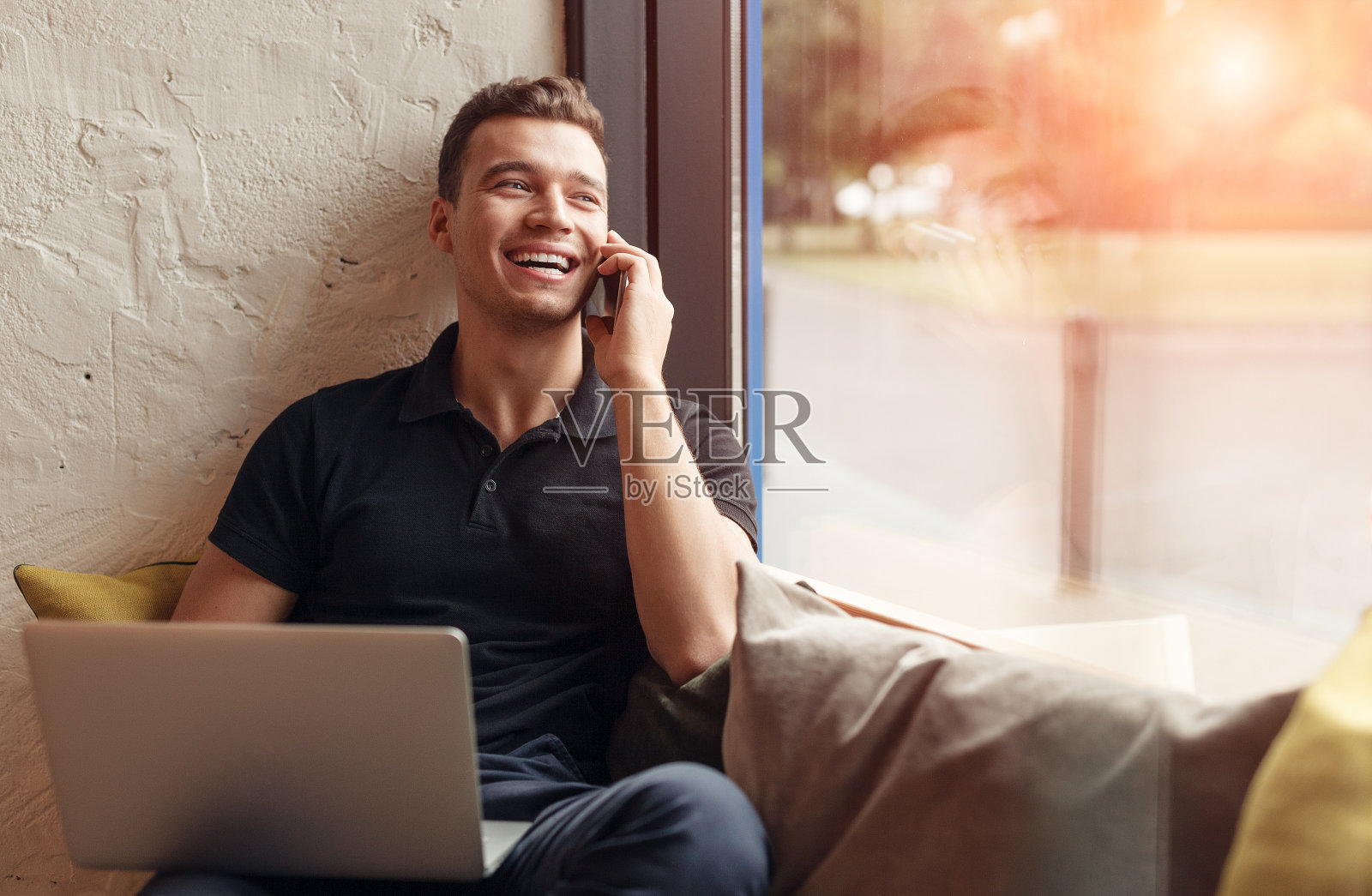一个拿着笔记本电脑在打电话的笑男人照片摄影图片