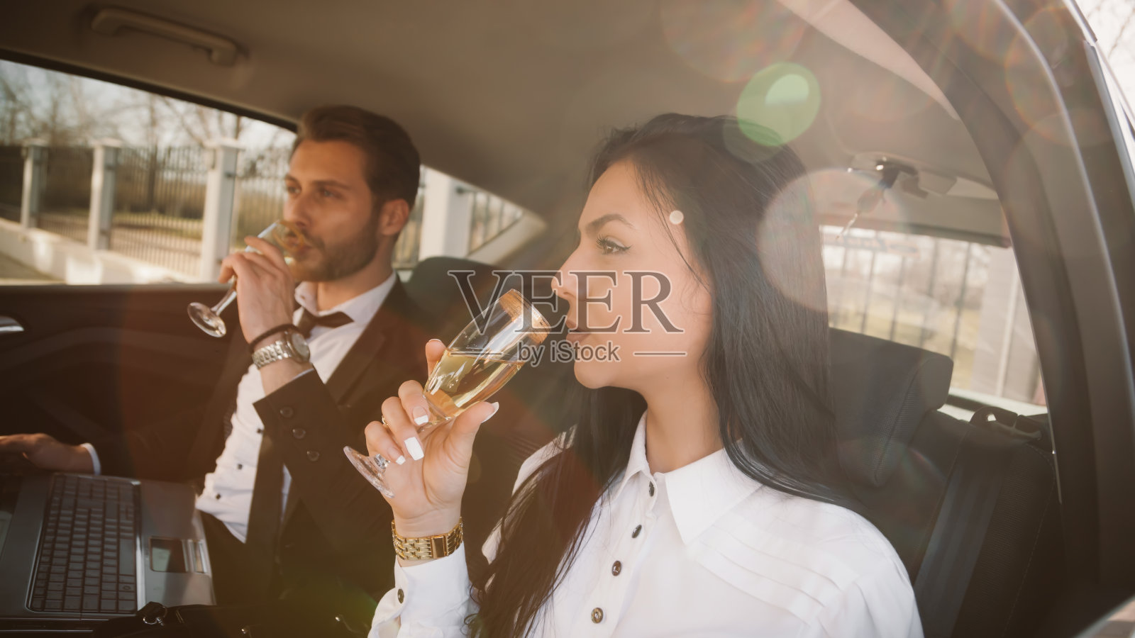 商务人士在长途商务旅行后在车里喝香槟照片摄影图片