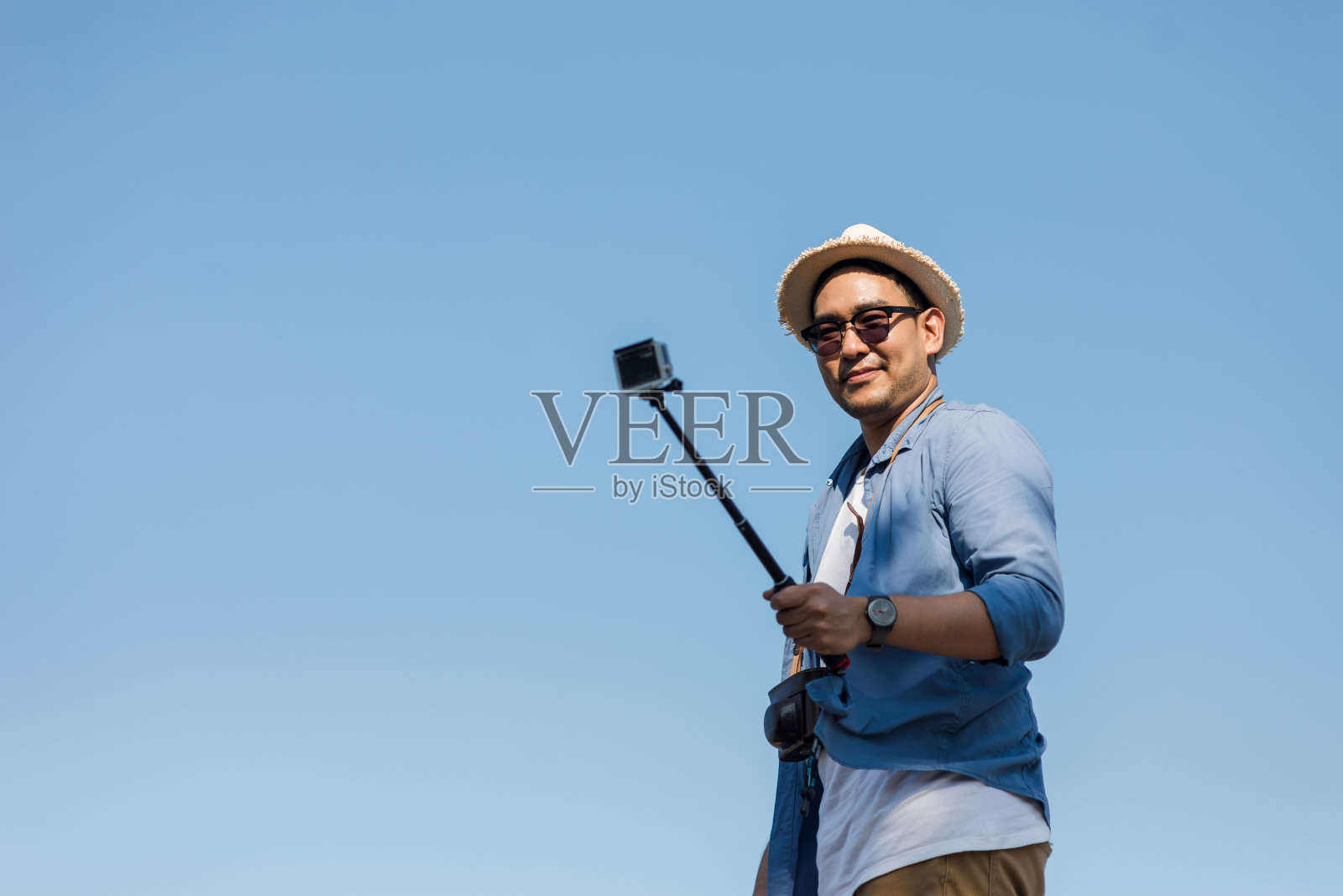 快乐的亚洲游客用相机棒与蓝天合影。照片摄影图片