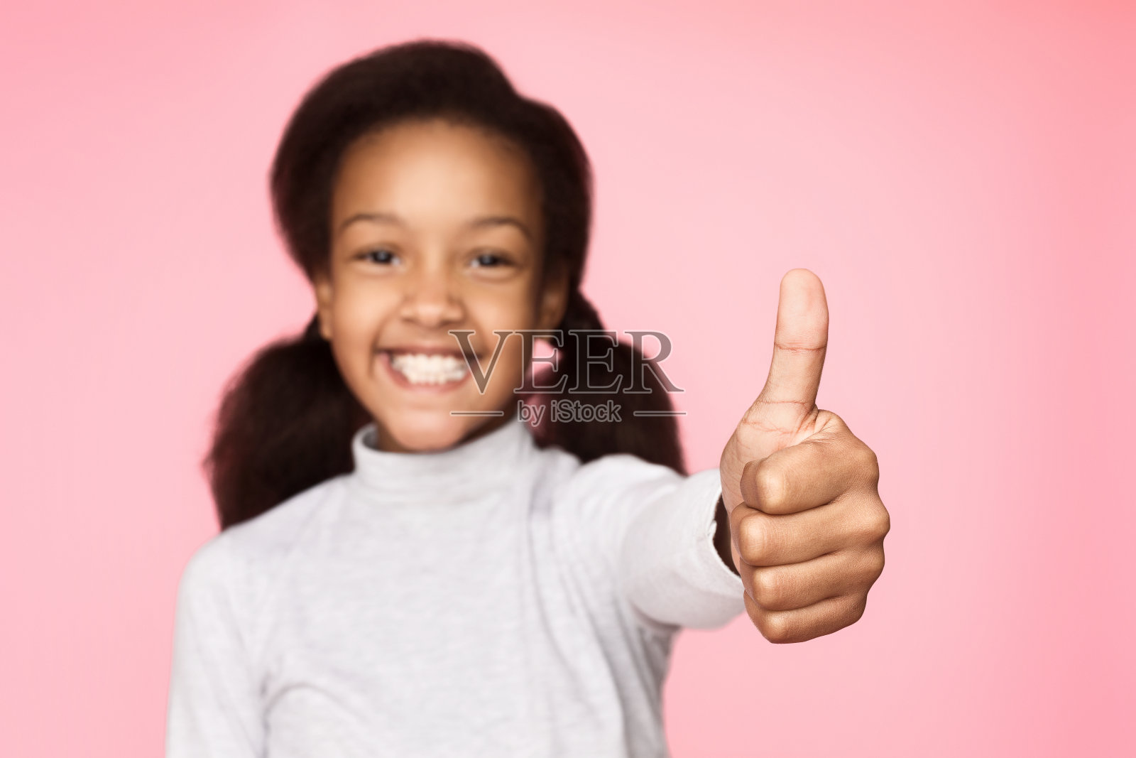 非裔美国女孩在粉红色的背景上竖起大拇指照片摄影图片