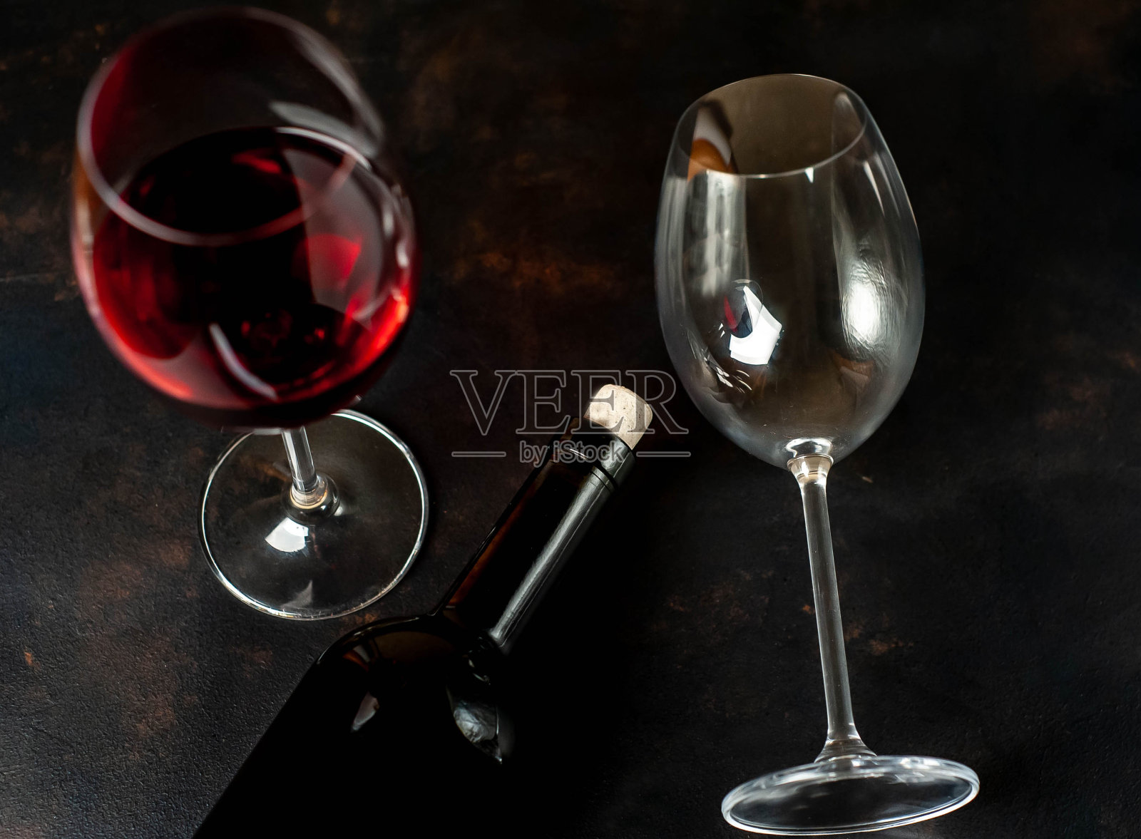 水泥背景下的一瓶葡萄酒和一杯葡萄酒照片摄影图片