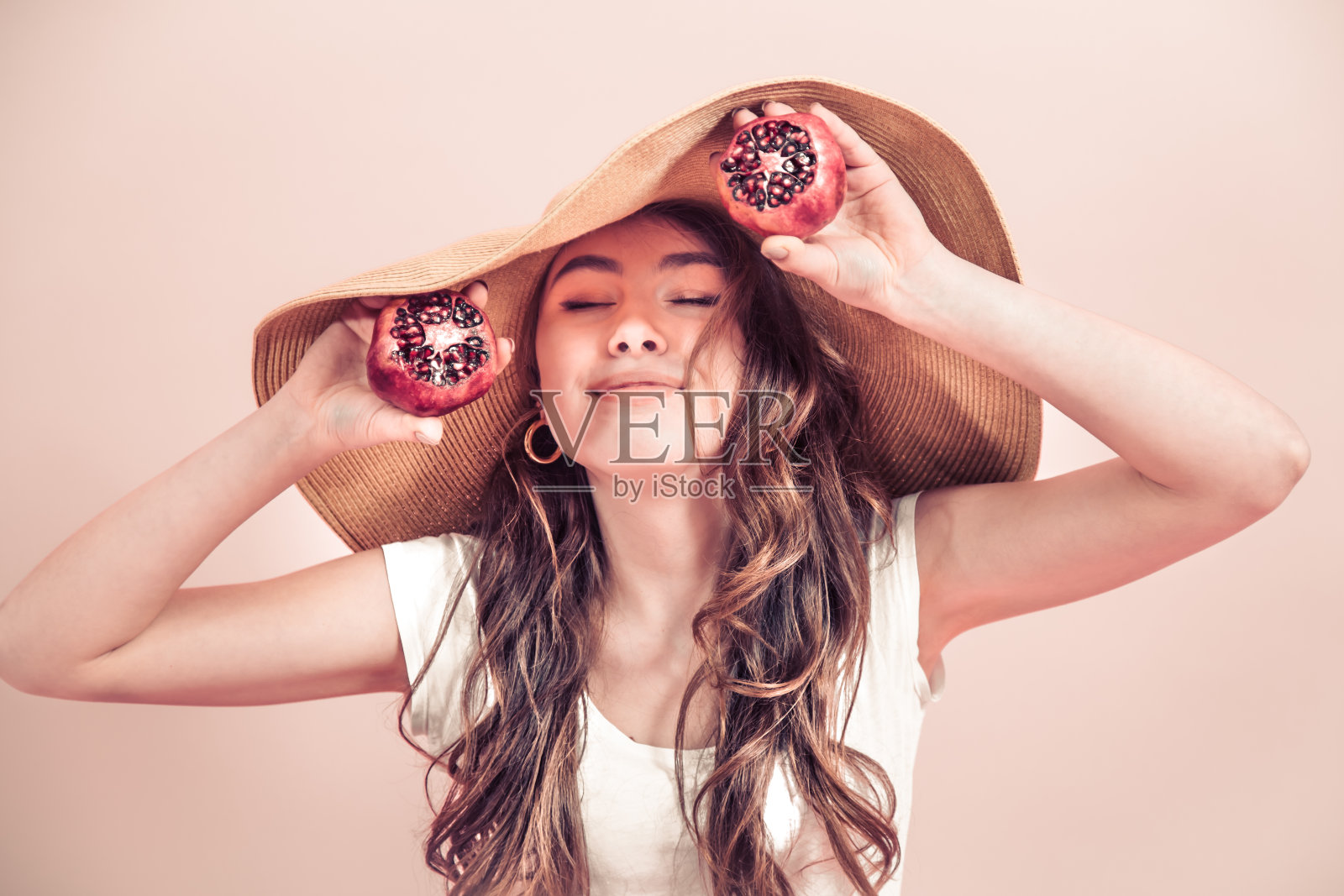一个女孩的肖像，戴着夏天的帽子和水果在一个彩色的背景照片摄影图片