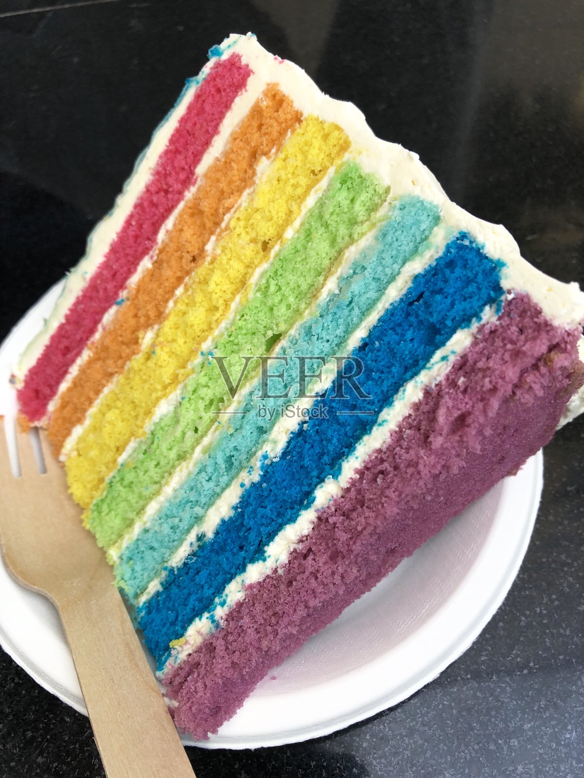 彩虹蛋糕的切片图像显示了多色海绵层与奶油糖霜的照片照片摄影图片