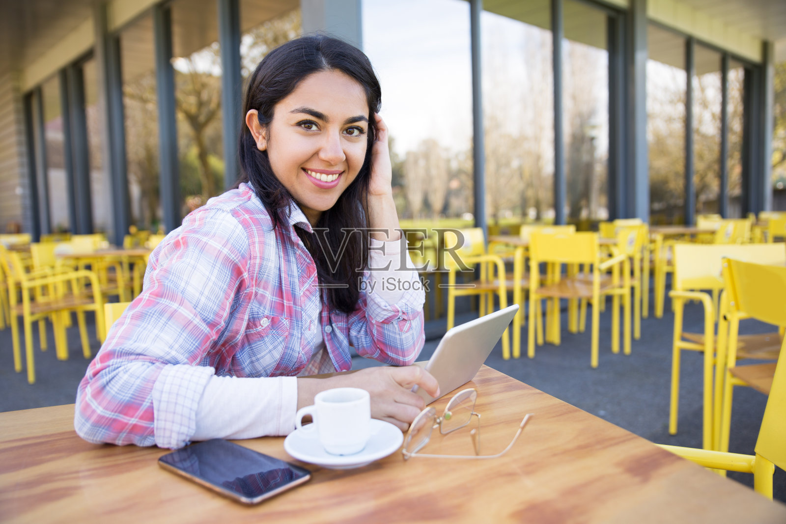微笑的女士使用小工具和在咖啡馆喝咖啡照片摄影图片