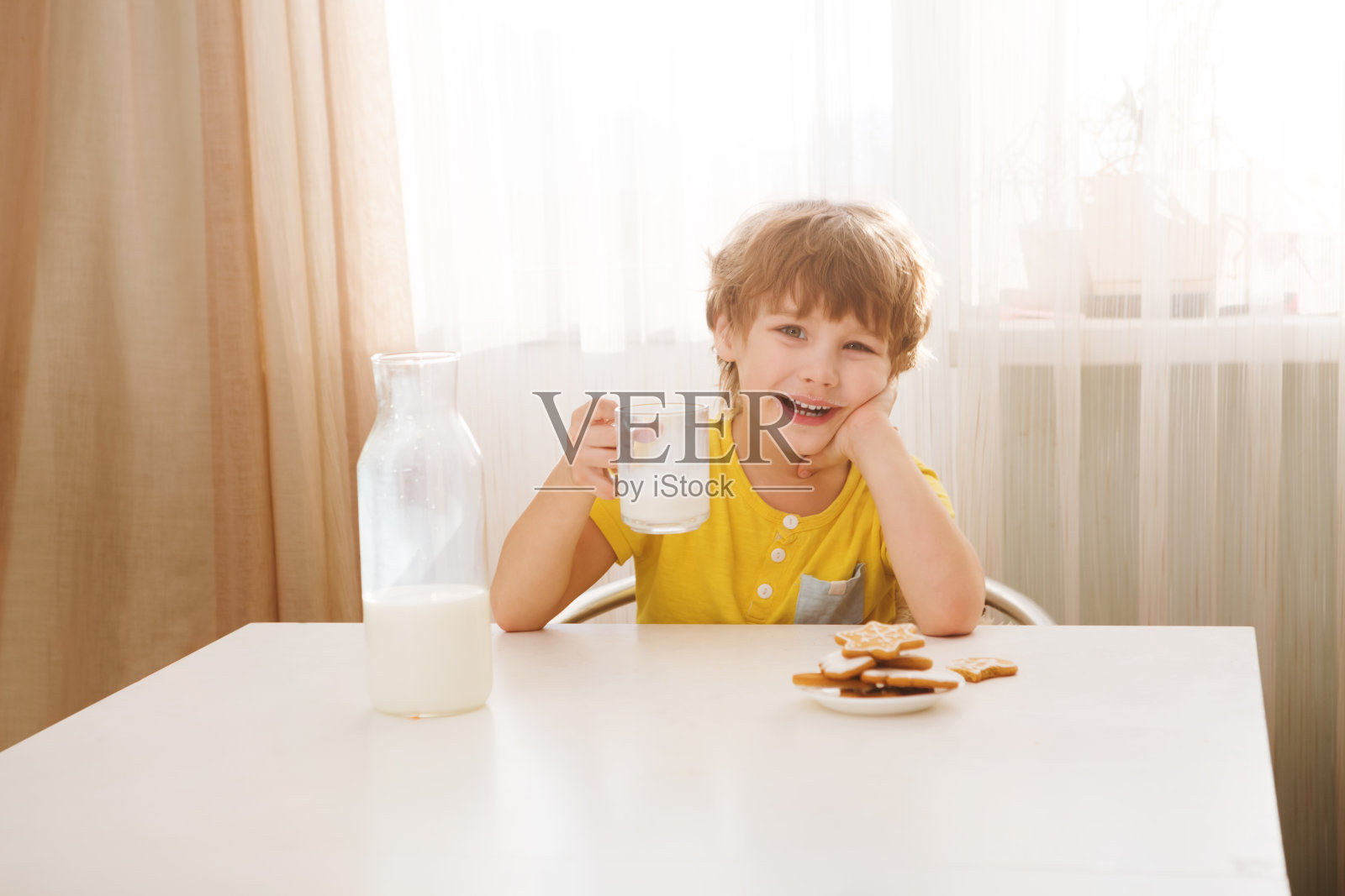 小男孩在厨房里喝牛奶，吃饼干照片摄影图片