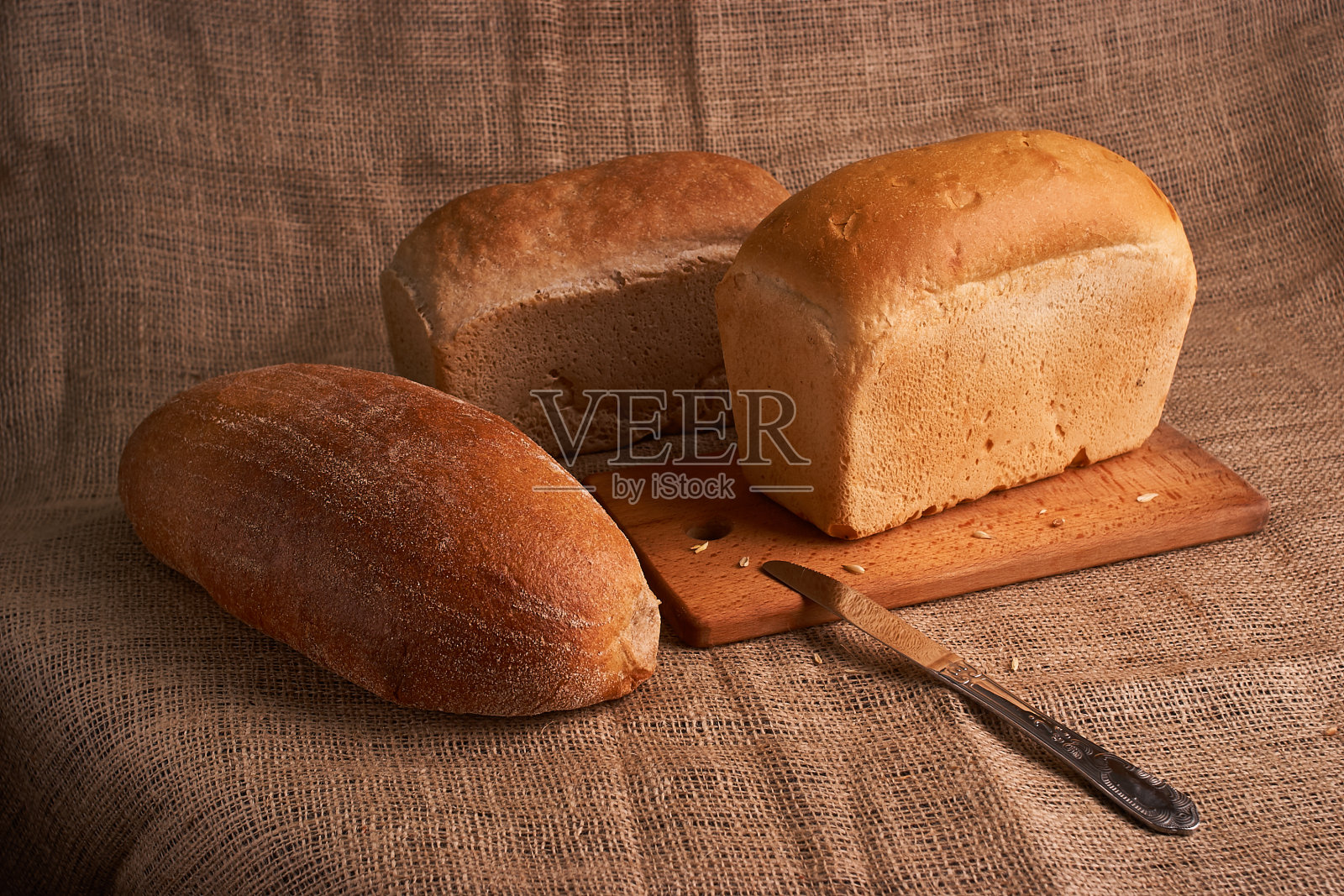 不同的面包和小麦放在质朴的桌子上。选择性聚焦，特写照片摄影图片