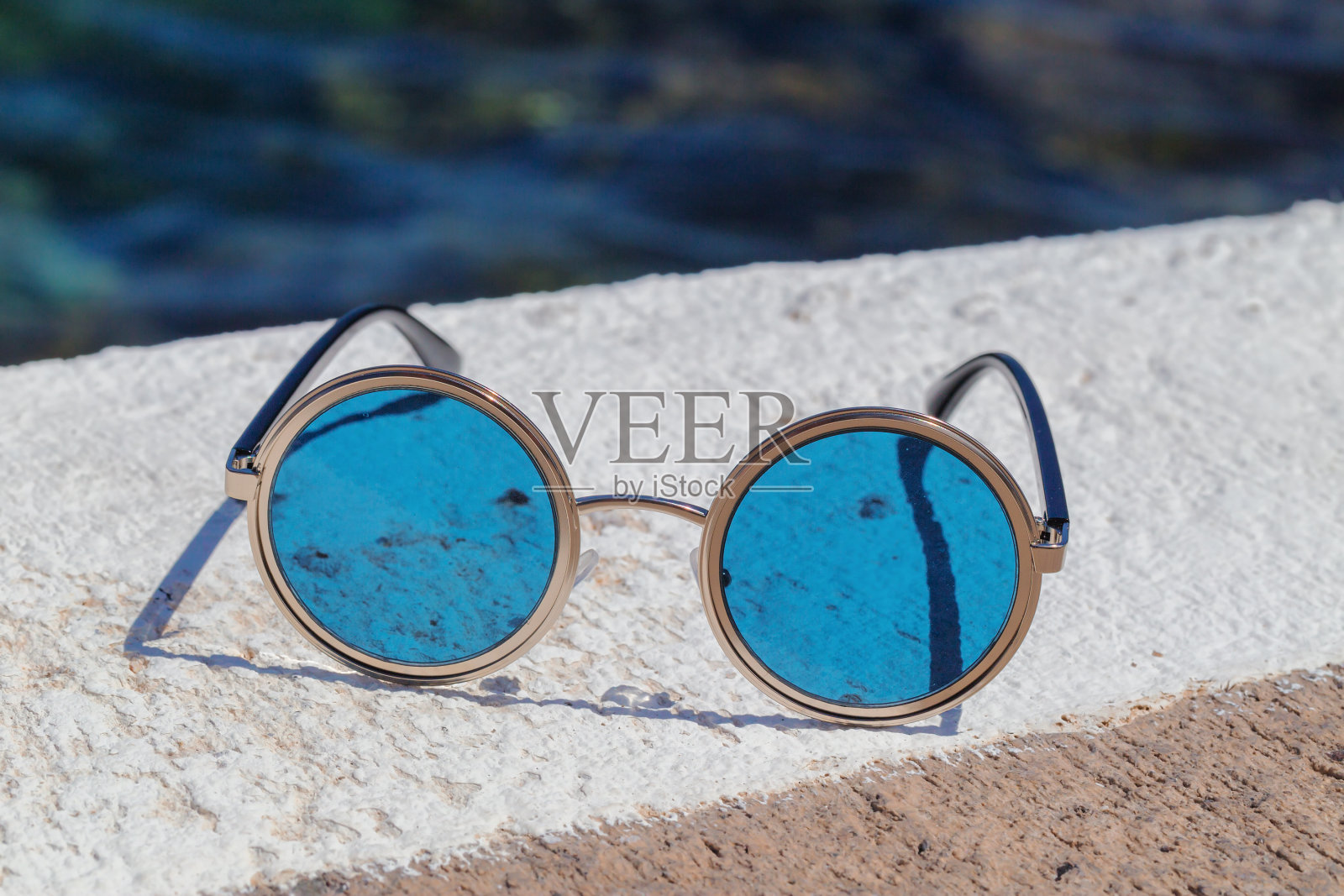 圆形太阳镜和蓝色眼镜在石头上照片摄影图片