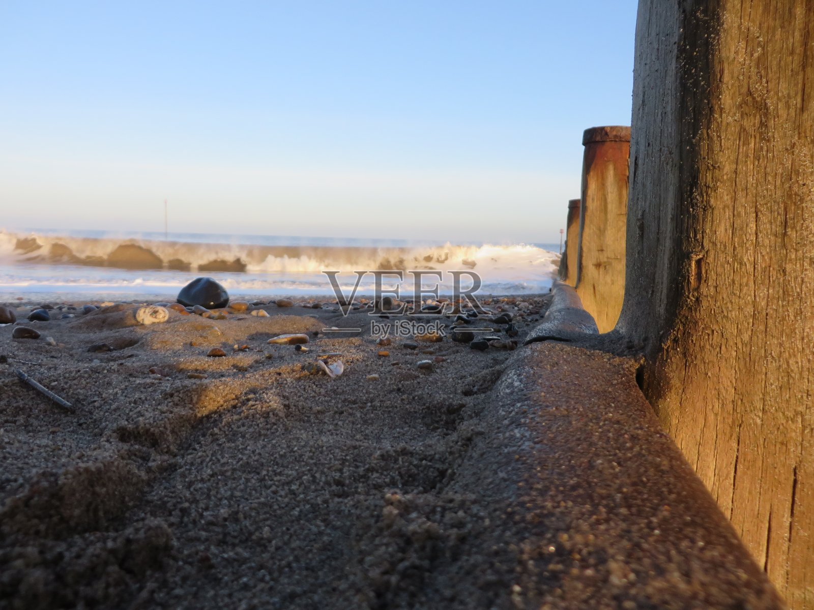 在波涛边缘。一个石头，沙子，宁静的海滩与海浪冲击海岸。照片摄影图片