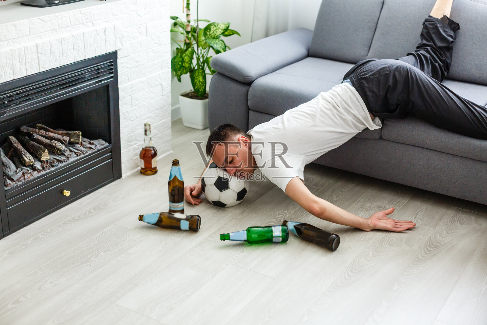 醉醺醺的年轻英俊男子在客厅的沙发上休息，头朝地板上。照片摄影图片
