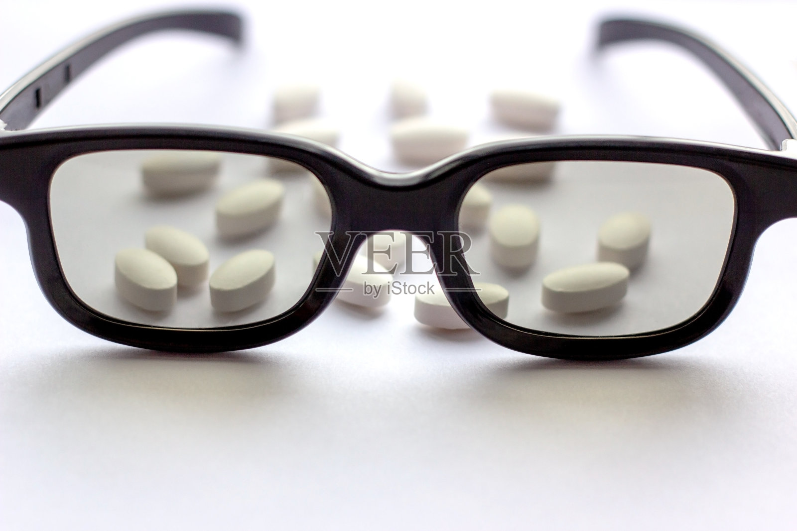白色药丸和药片，带眼镜，背景亮。药学和医学概念。专注于眼科疾病的制药行业照片摄影图片
