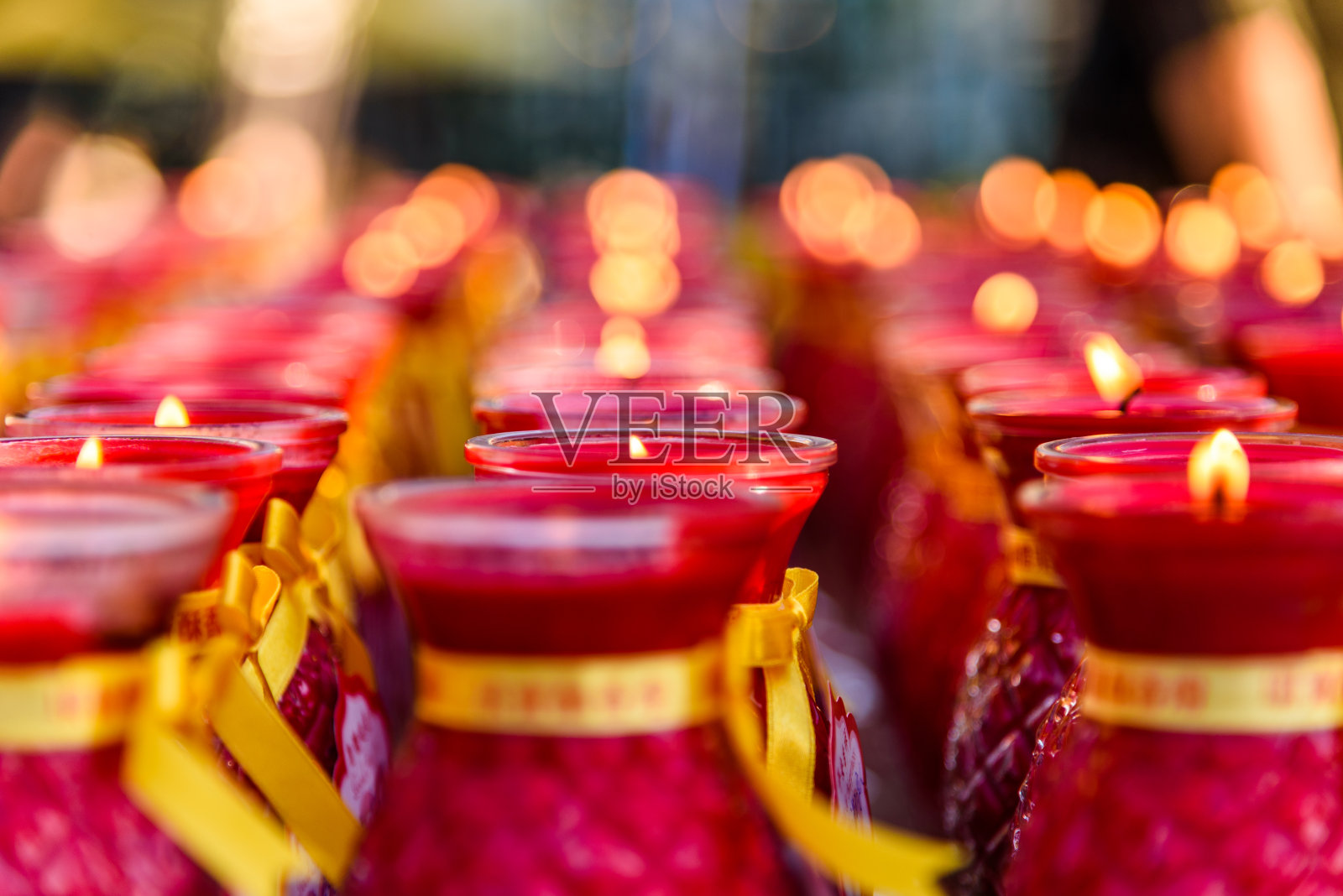 几排红色的佛教祈祷蜡烛渐渐消失在背景中照片摄影图片