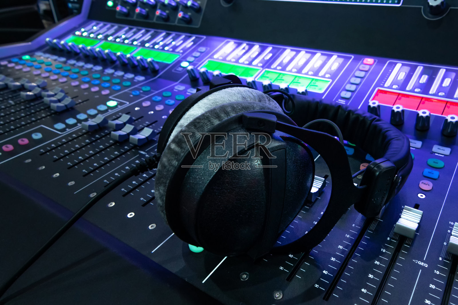 专业录音室混音控制台面板，配有录音、耳机和调节旋钮，电视设备。蓝色色调和近景图像与耀斑光效果。照片摄影图片