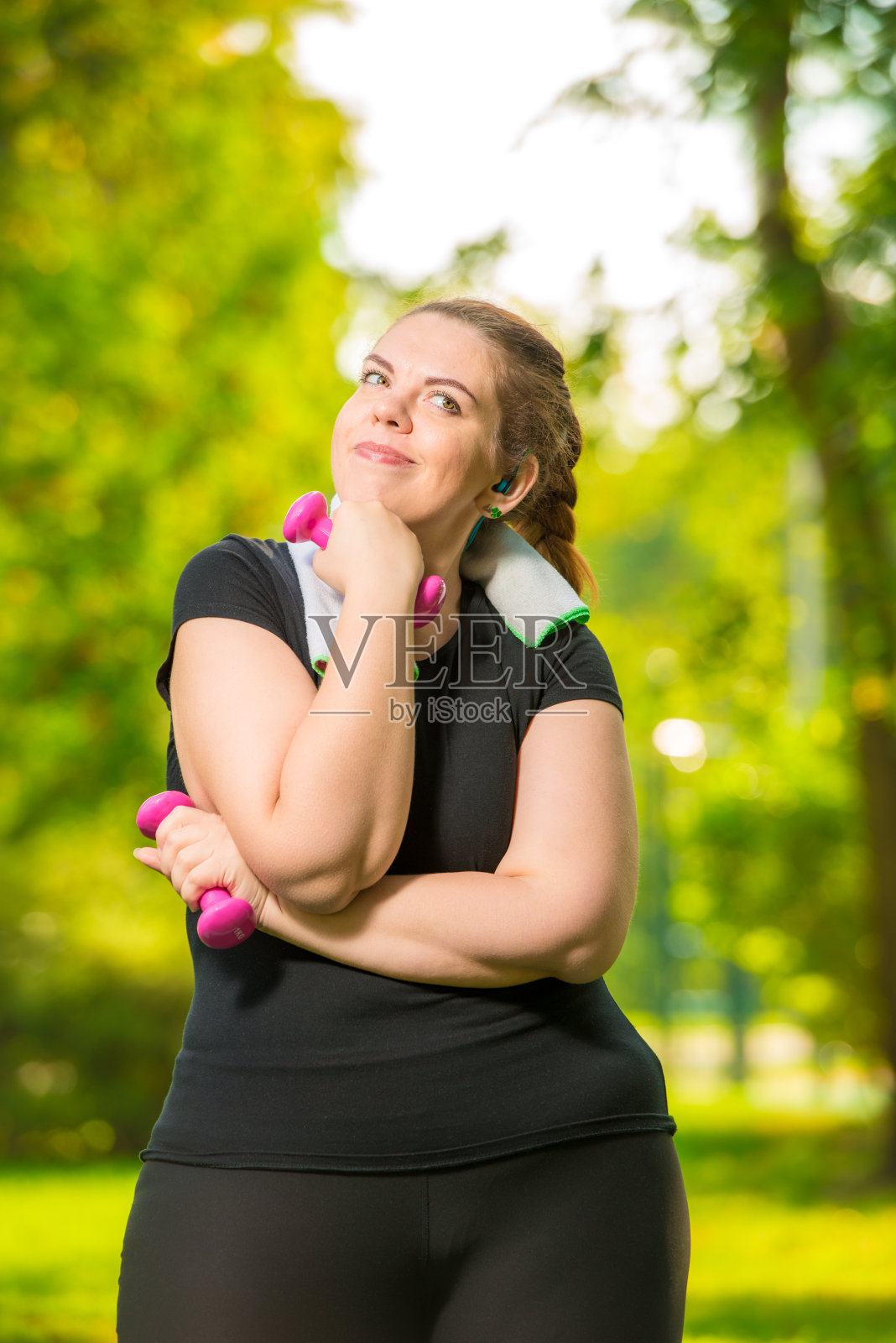 梦想着身材苗条的模特在一个夏天的公园里用哑铃锻炼照片摄影图片
