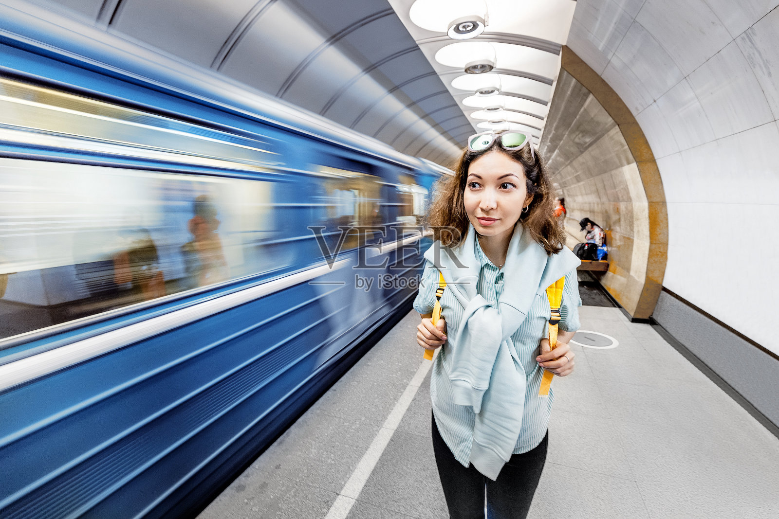 年轻的亚洲女孩的肖像与行李在地铁站等待火车。运动速度模糊照片摄影图片