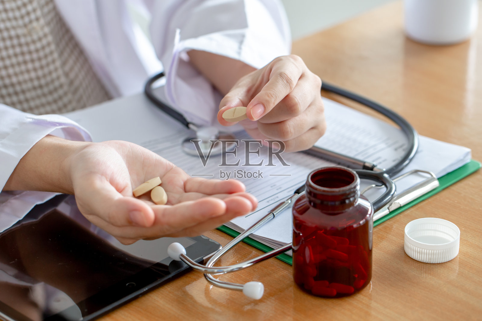 在诊所里，亚洲女医生向病人介绍药瓶。照片摄影图片