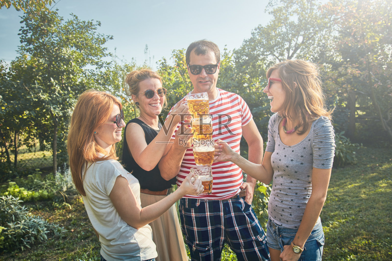 一群年轻人在户外享受和欢呼啤酒。照片摄影图片