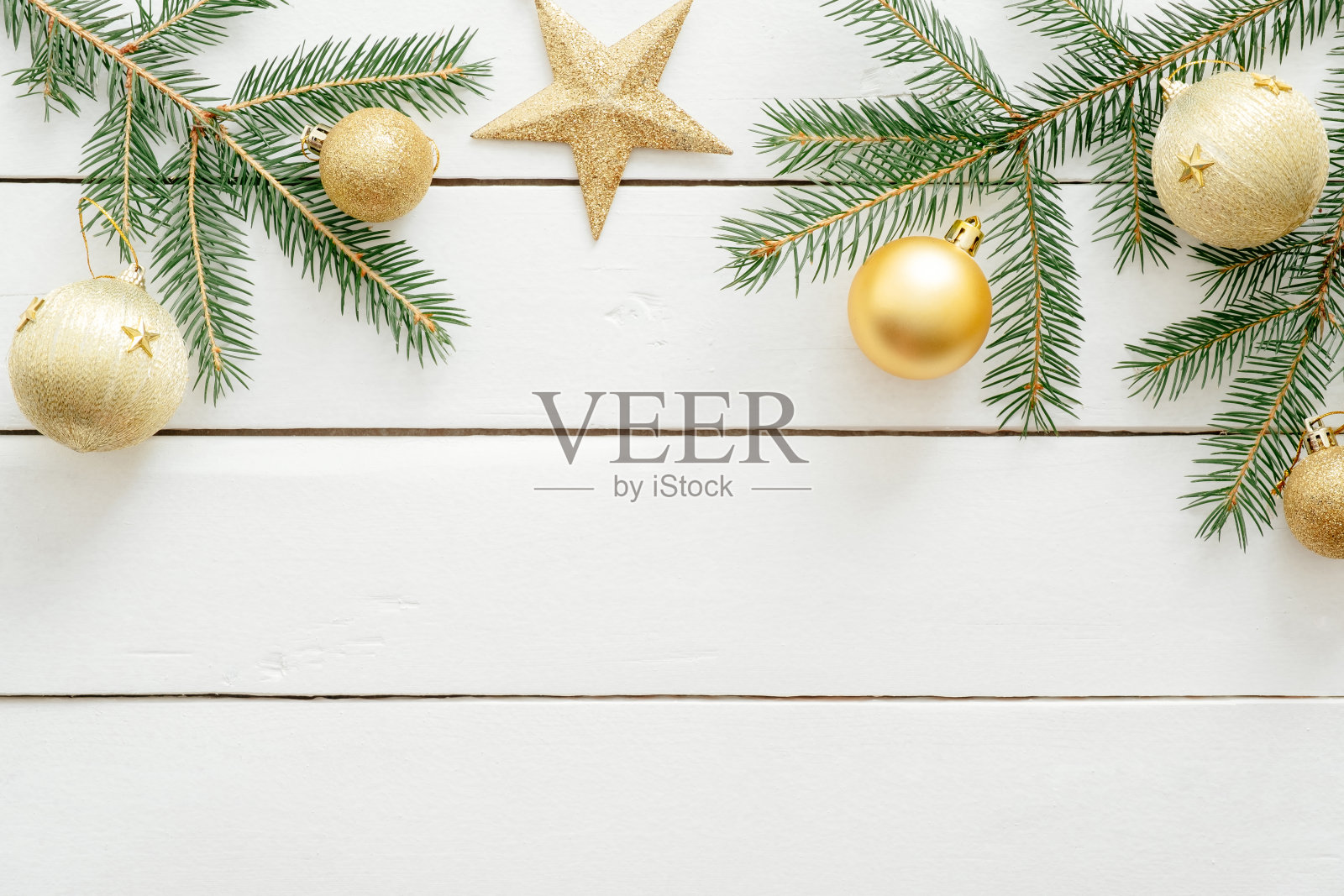 扁平的金色圣诞装饰品和冷杉树枝放在木制的白色桌子上。圣诞框，上边框。平铺，俯视图，拷贝空间。圣诞节、新年、寒假概念。插画图片素材